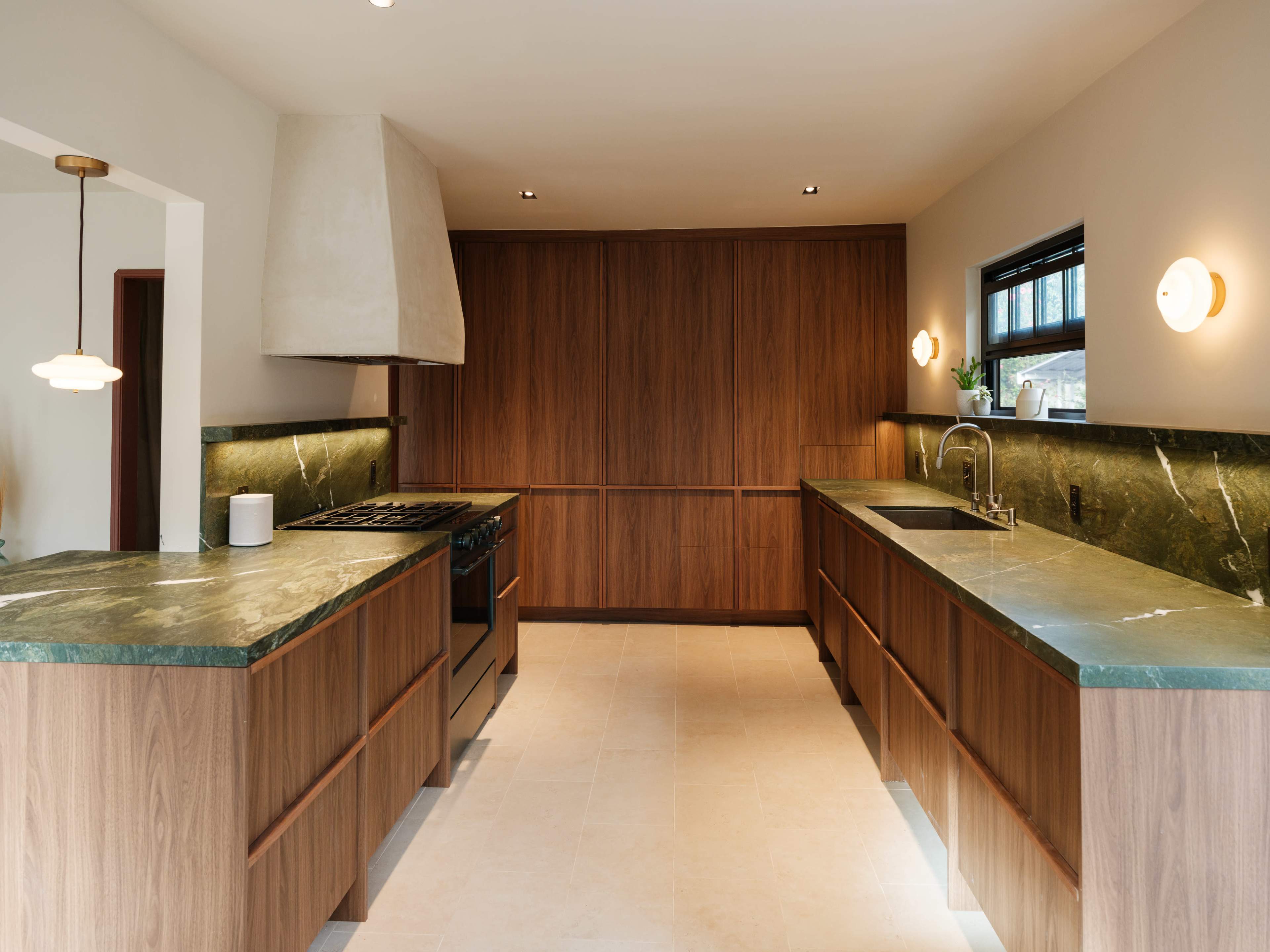 The image shows a modern kitchen with wooden cabinets, green stone countertops, a range hood, and minimal lighting fixtures.