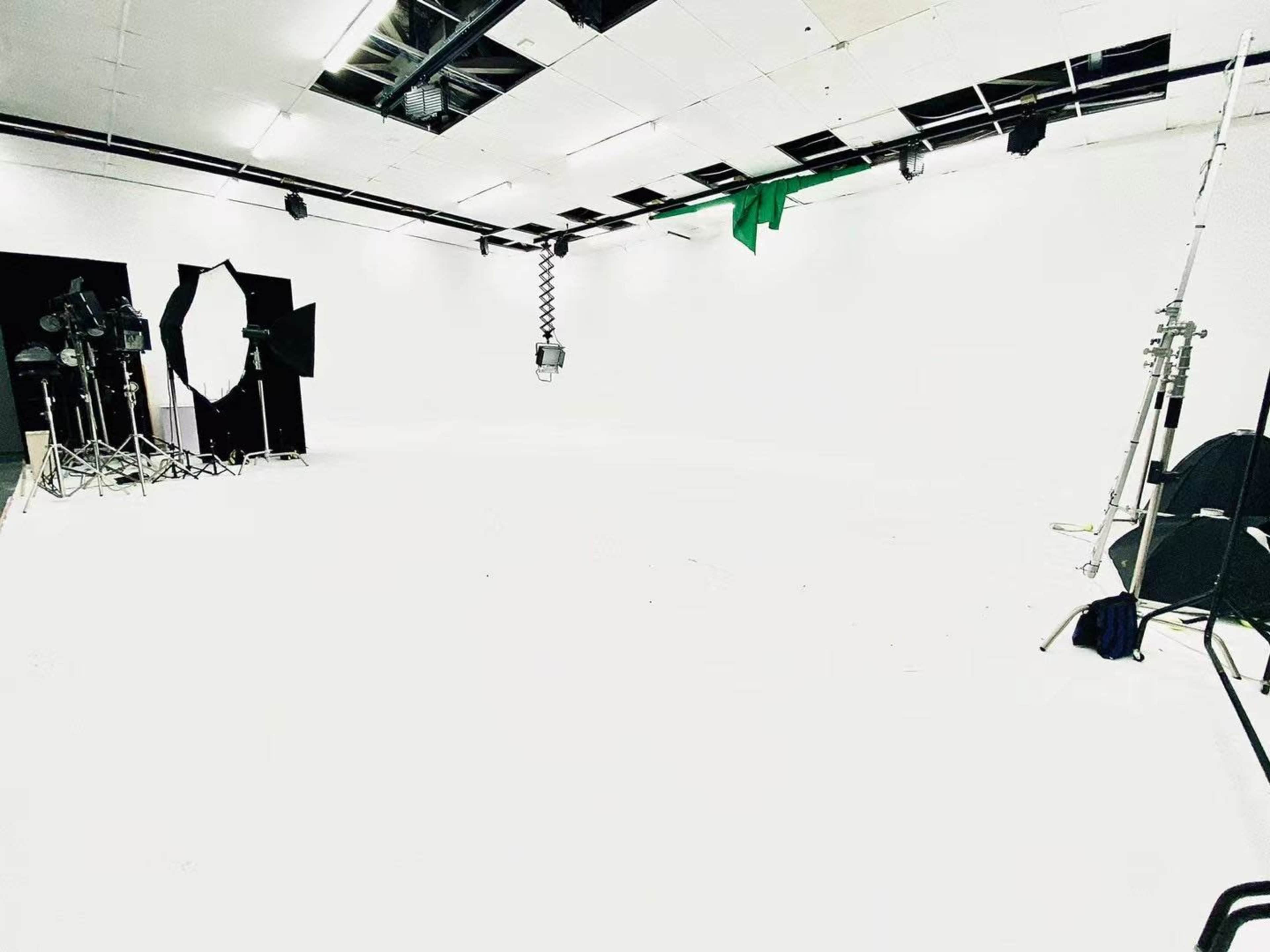An empty white studio with lighting equipment and backdrops set up around the space.