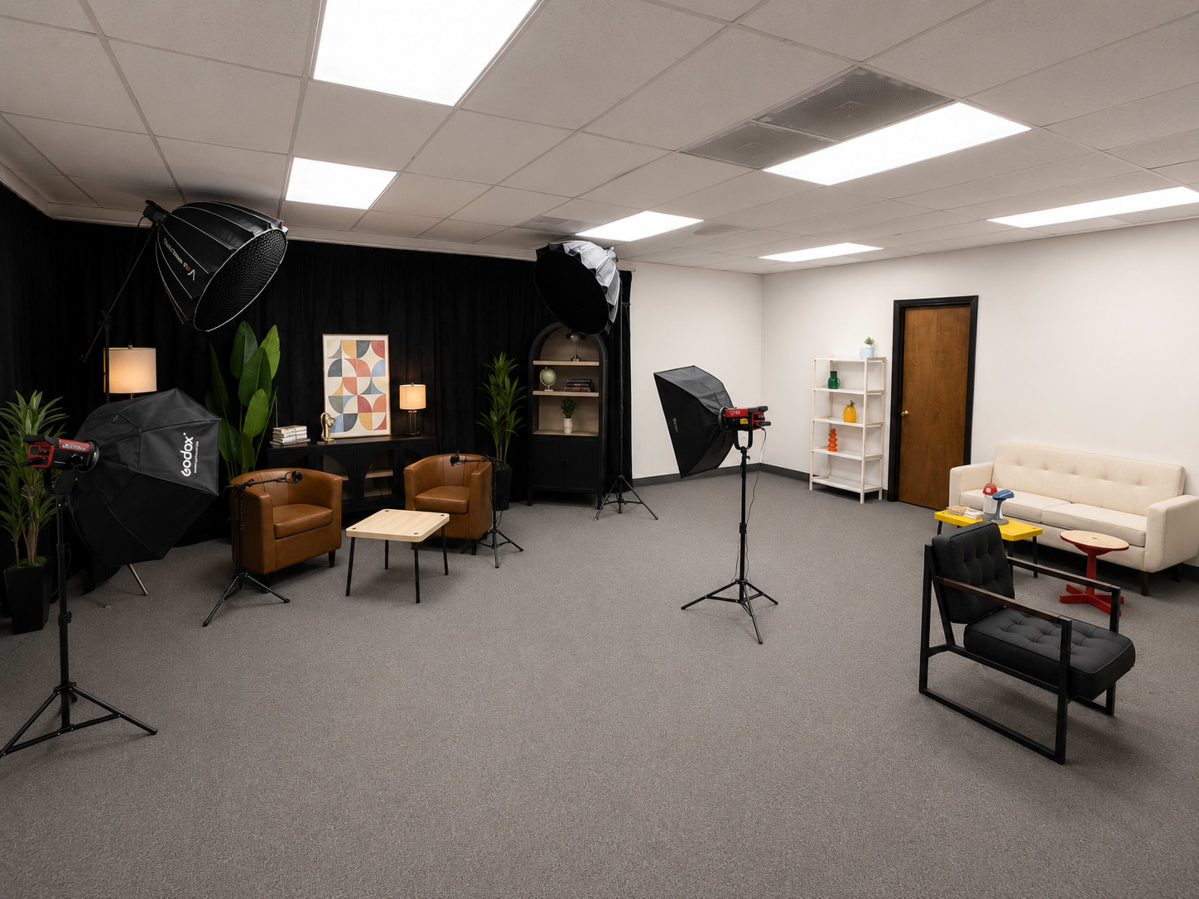 The image shows a well-lit studio space set up for photography, featuring a variety of seating arrangements, lighting equipment, and decorative elements on the walls.