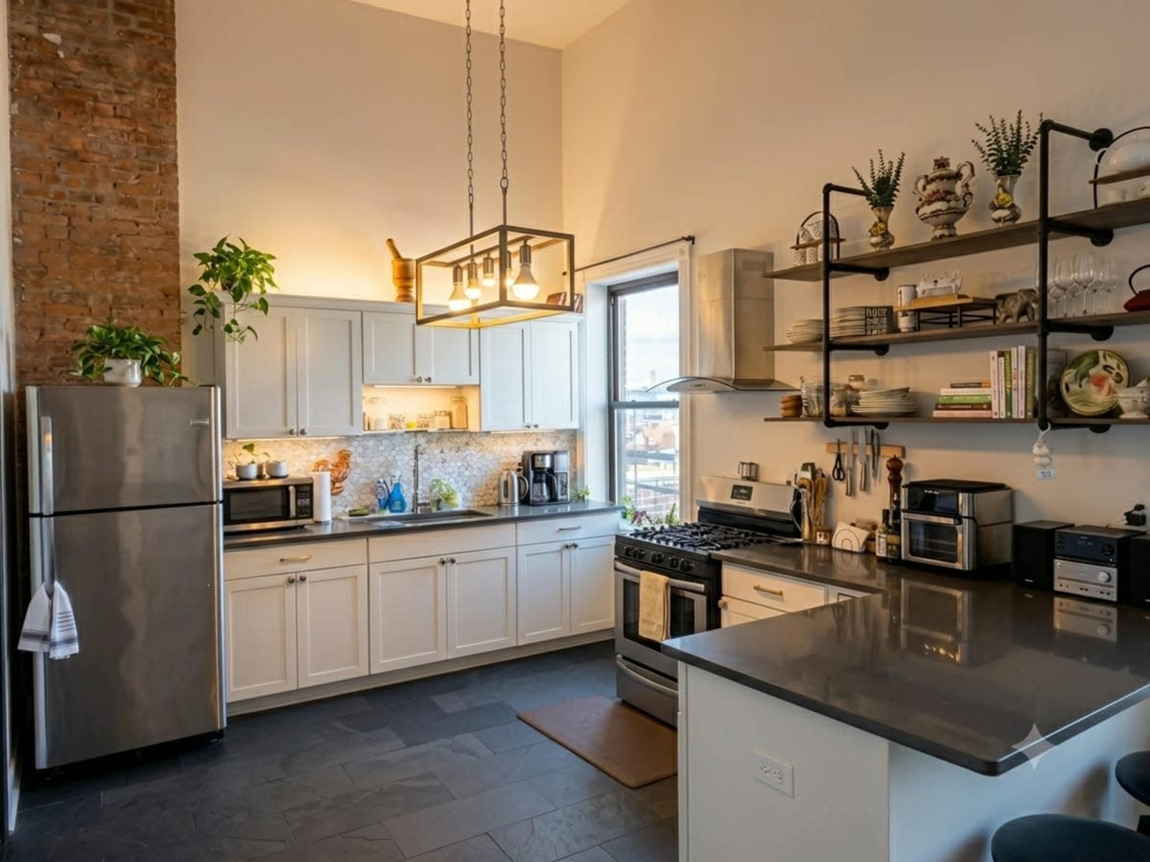 A modern kitchen features stainless steel appliances, white cabinetry, a stone wall, and open shelving displaying kitchenware and plants.