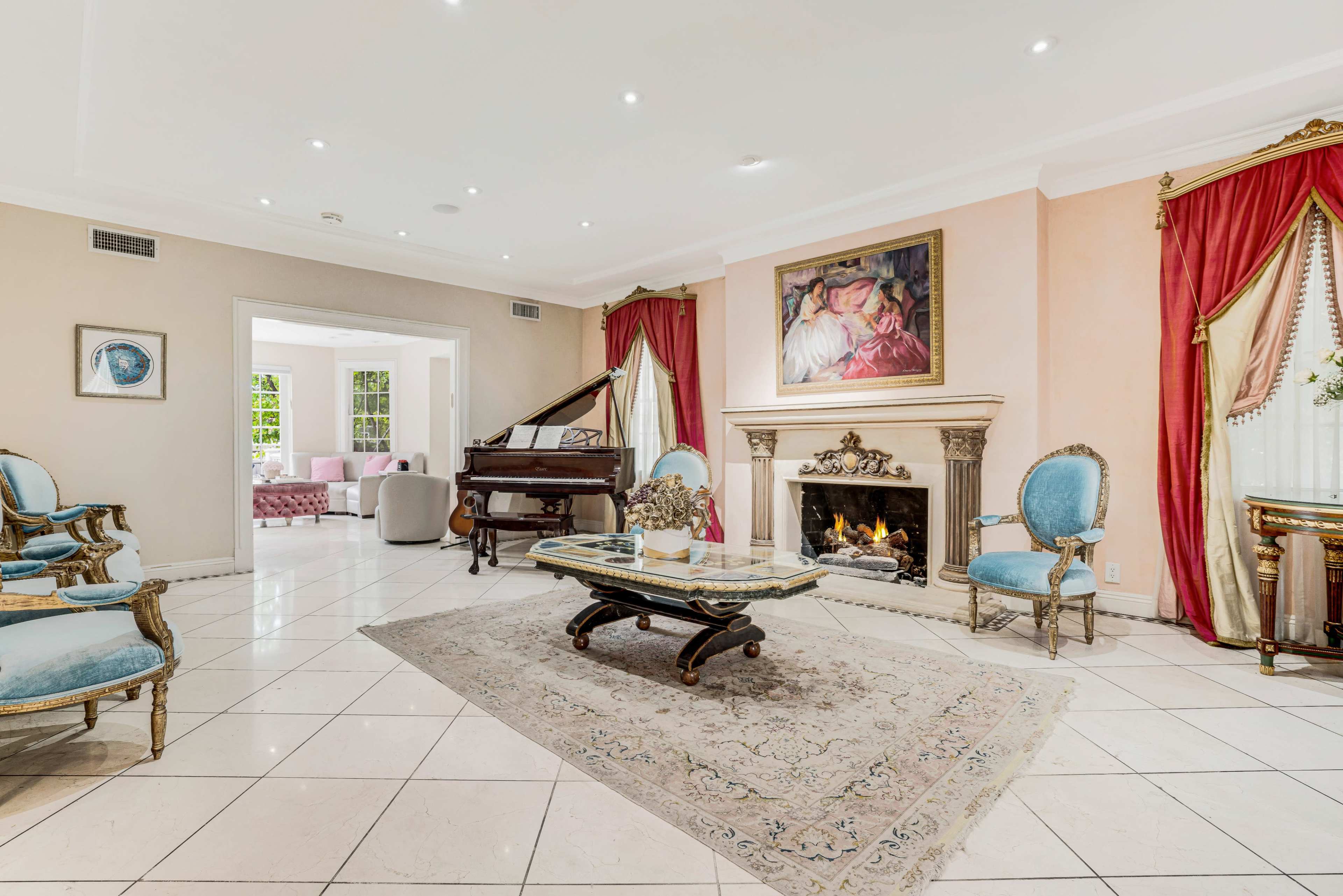 The room features a grand piano near a fireplace, with ornate furniture and a large painting on the wall.