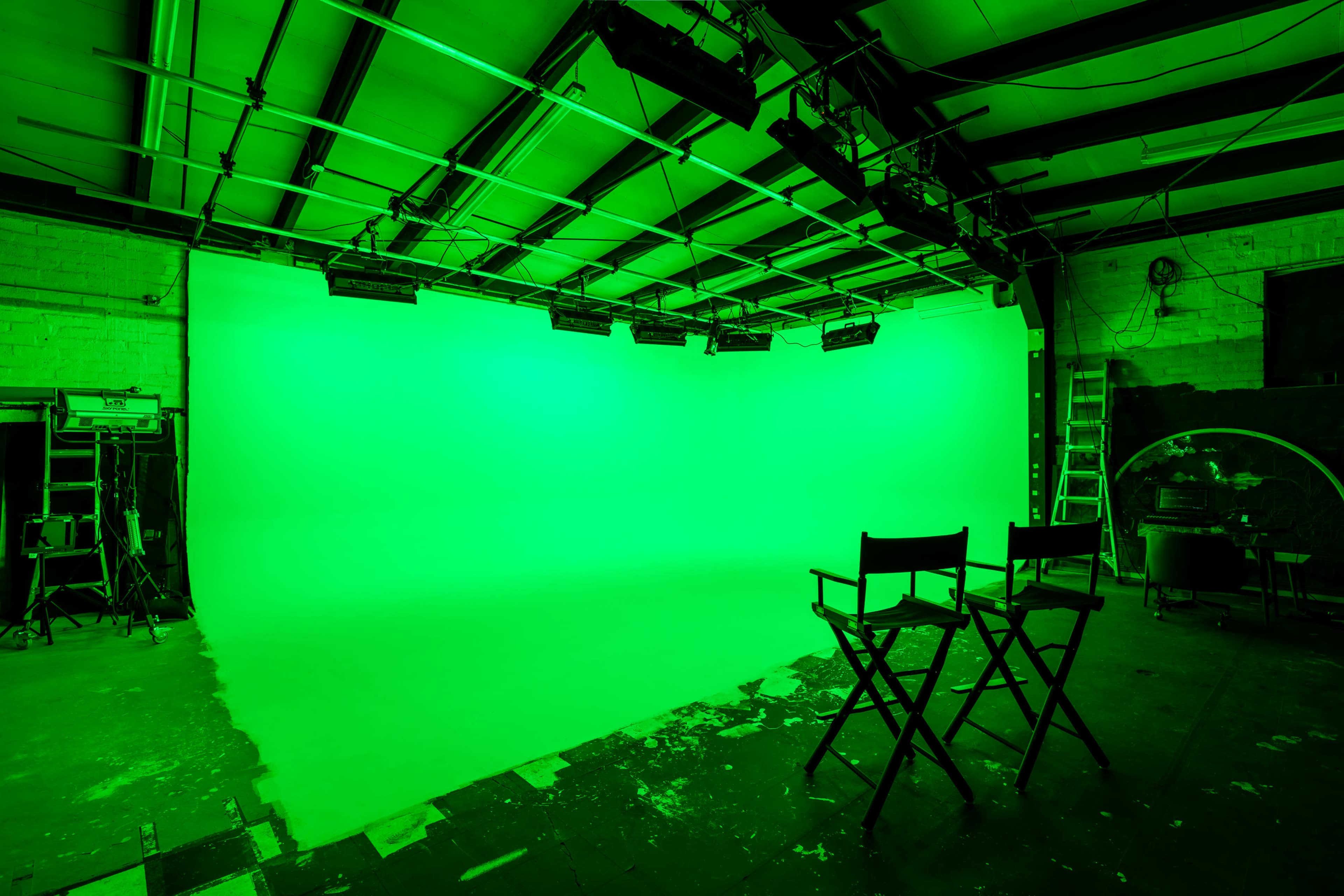 A green screen studio with two director's chairs and equipment visible in the background.