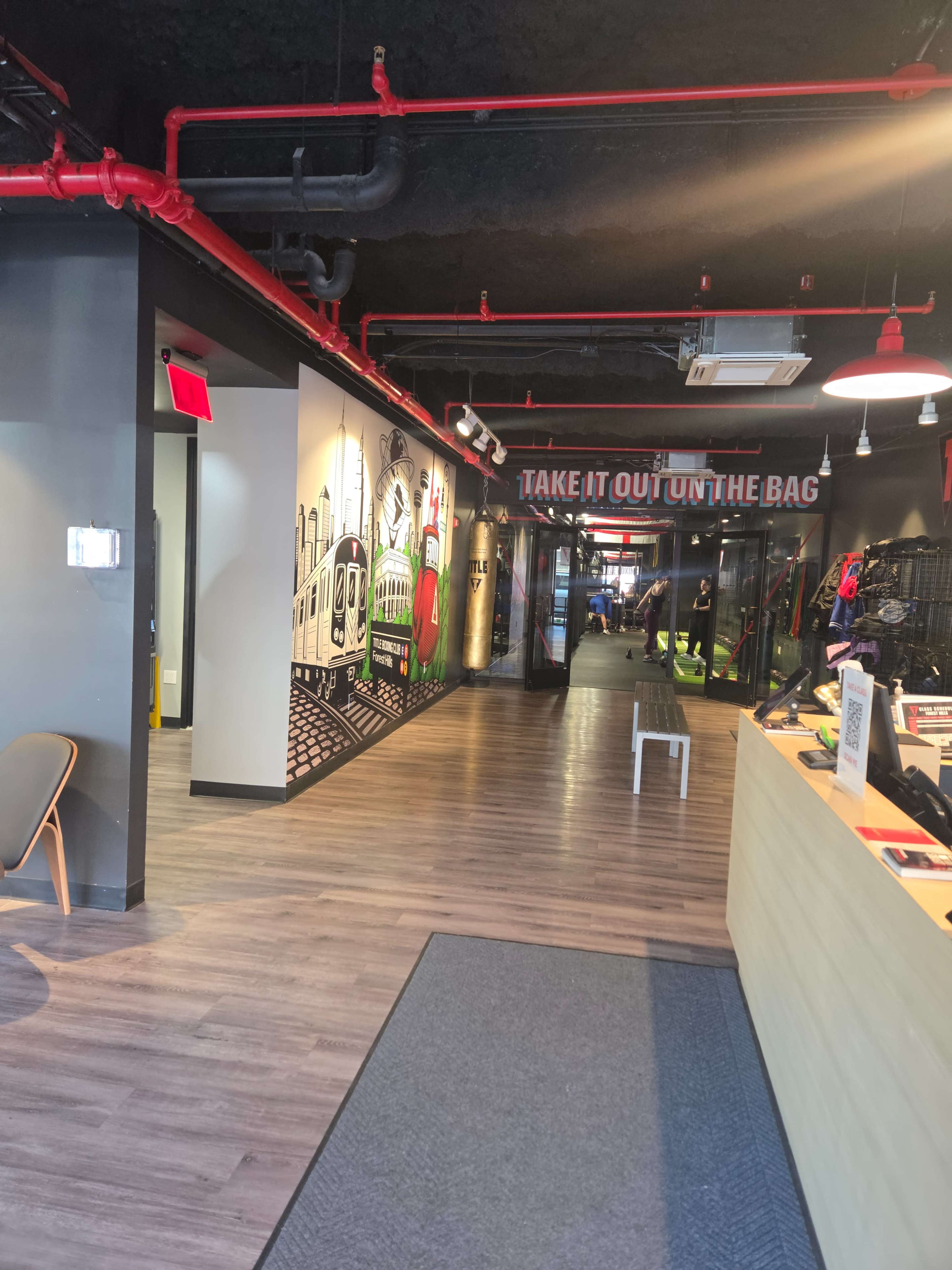 The image shows a modern interior of a retail space with colorful murals, exposed red piping, and a combination of wood and industrial design elements.
