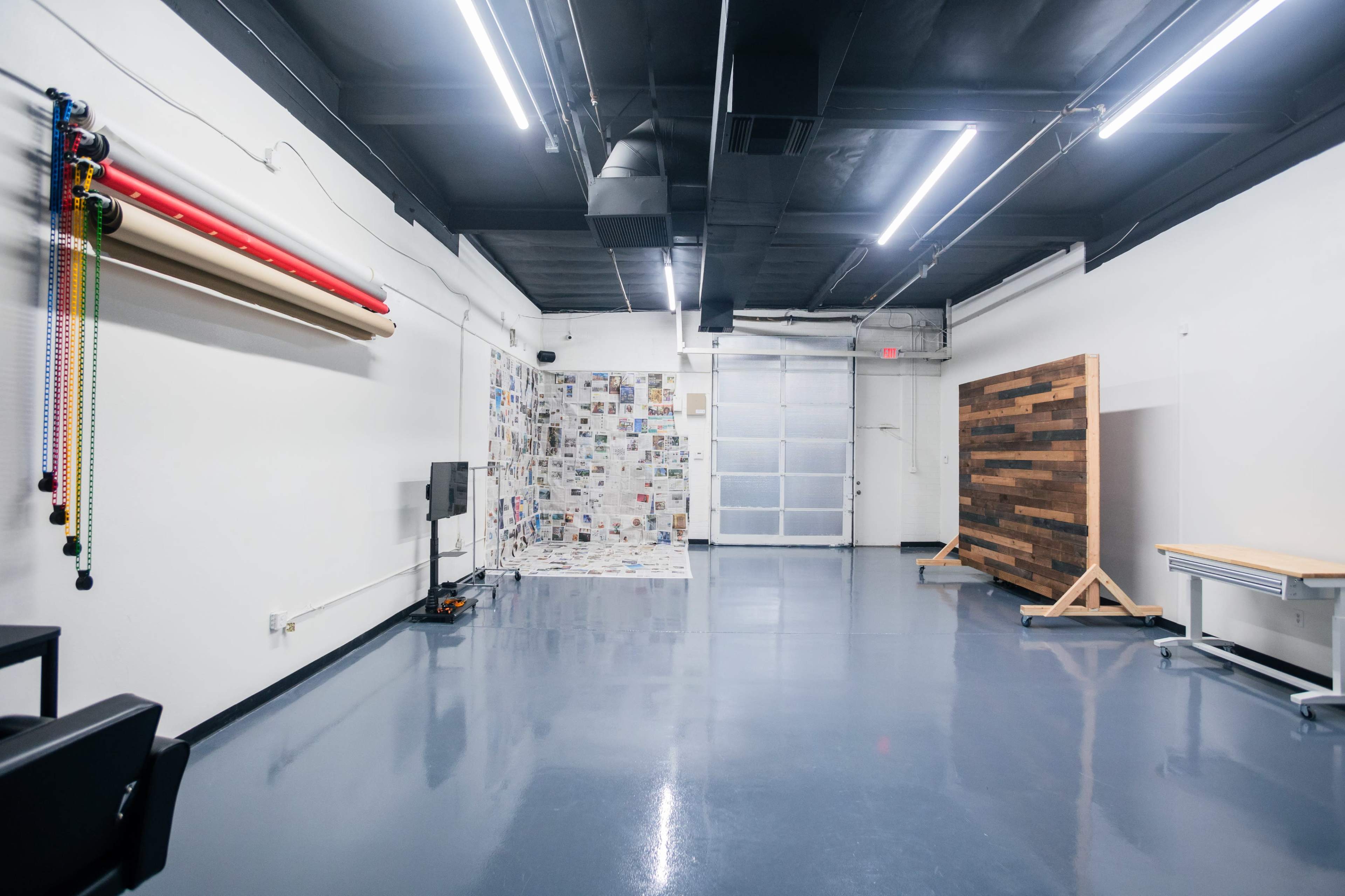 A spacious, well-lit indoor area with various wall textures, a wooden partition, and equipment along one side.