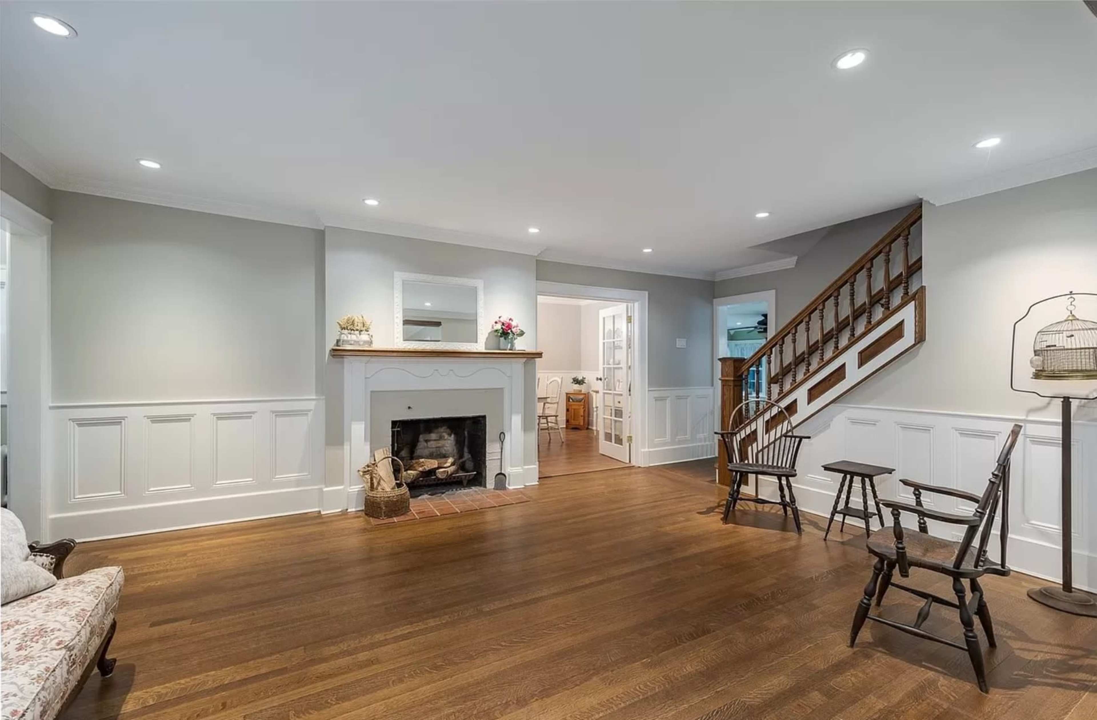 A well-lit living room featuring a fireplace, wooden flooring, and a staircase leading to an upper level.