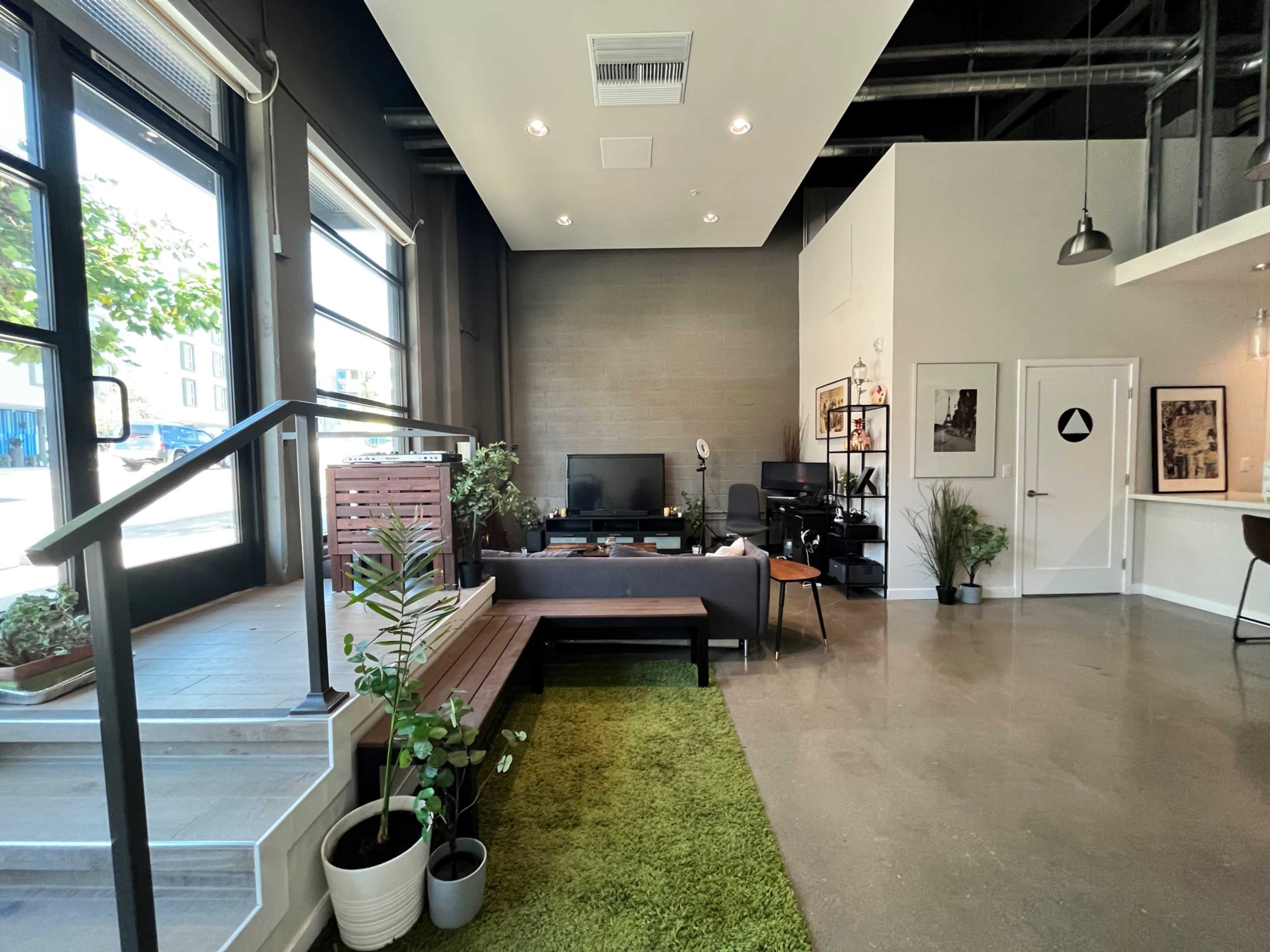 A modern open-concept living space with large windows, a seating area, and a small kitchen bar.