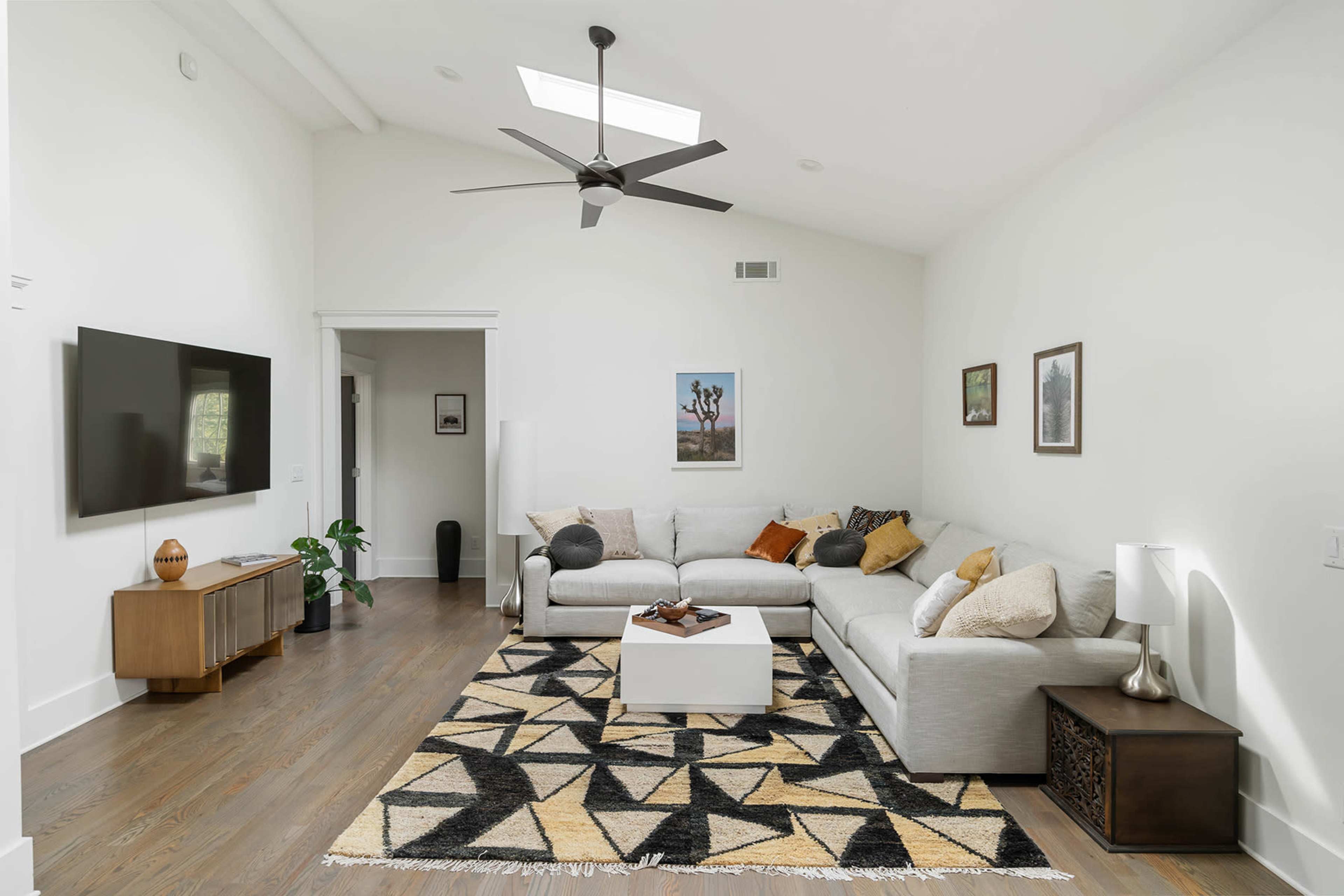 A modern, well-lit living room with a sectional sofa, a coffee table, and a patterned area rug.