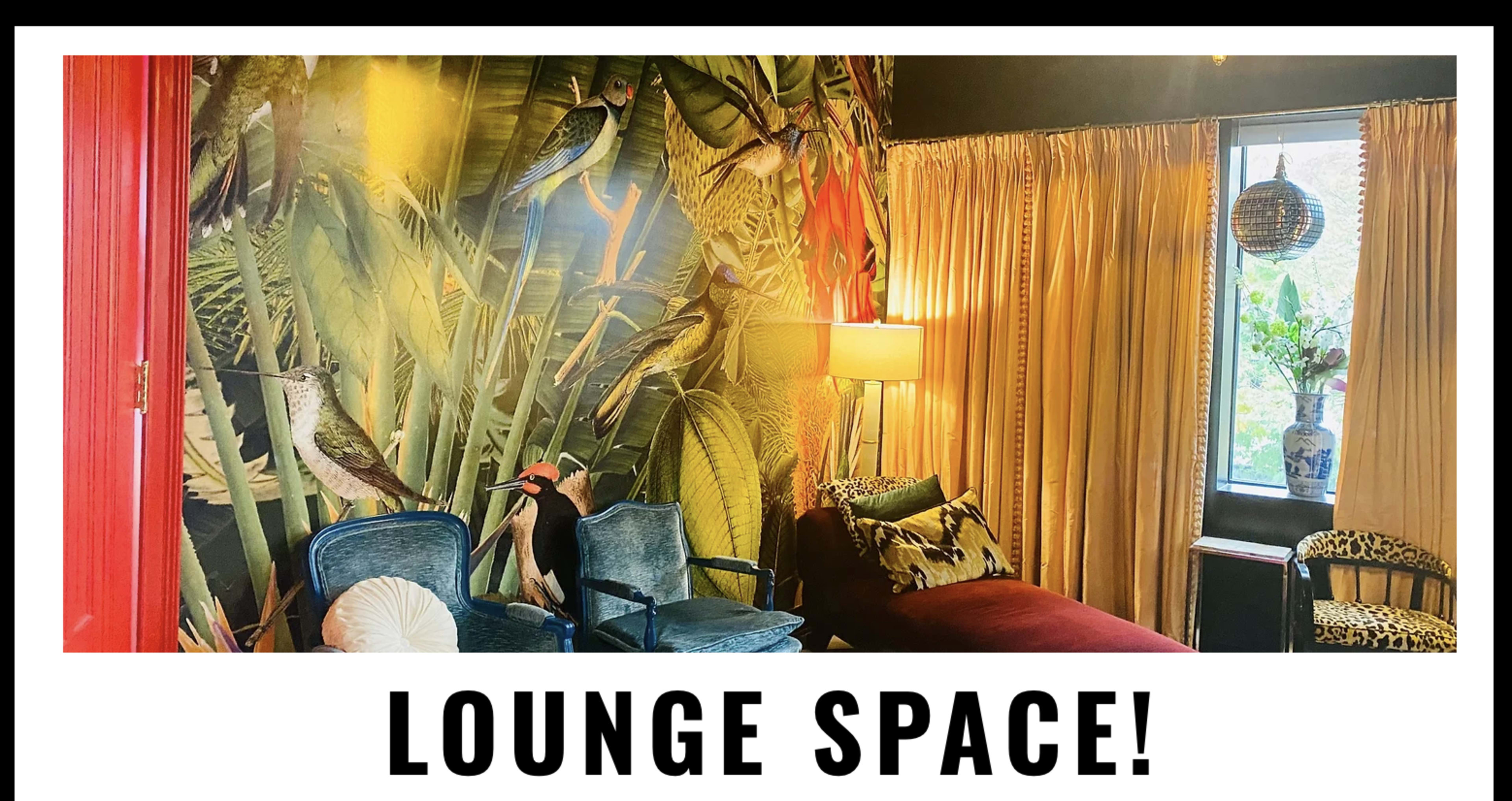 The image shows a vibrant lounge area featuring tropical-themed wallpaper, two upholstered chairs, a daybed, and large windows with drapes.