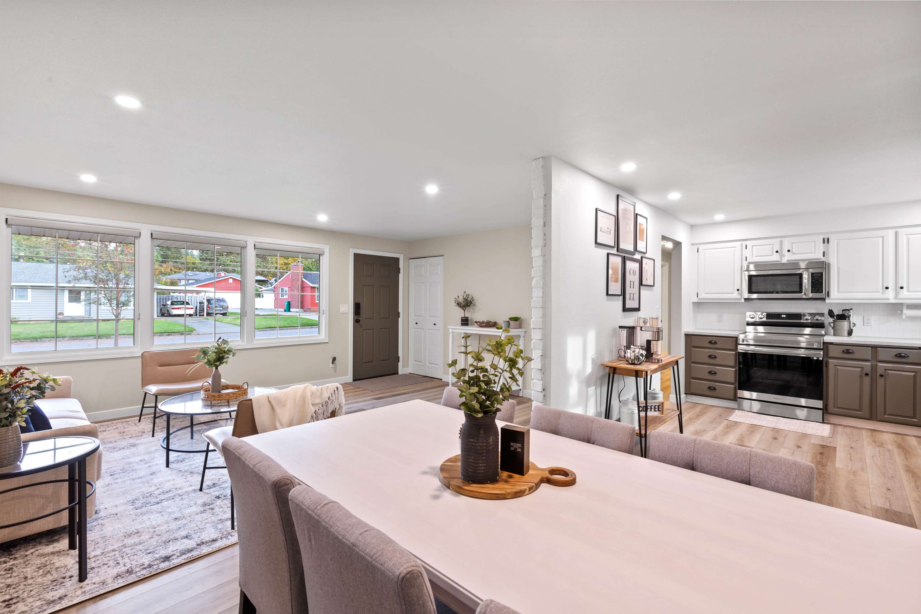 A modern open-concept living and dining area with a kitchen featuring stainless steel appliances and a dining table set for six.