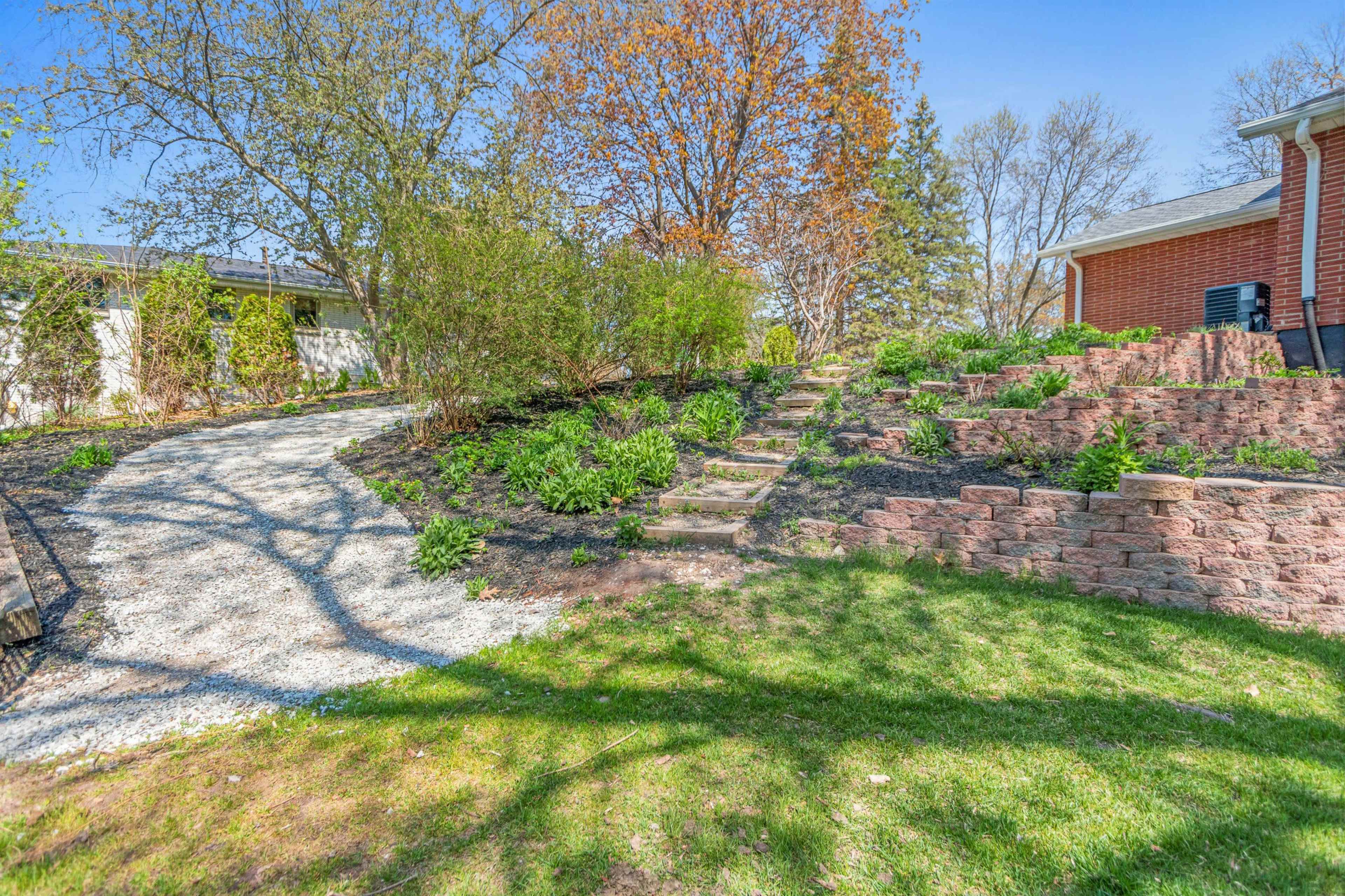 A landscaped garden with a gravel path leading to a set of stone steps surrounded by greenery.