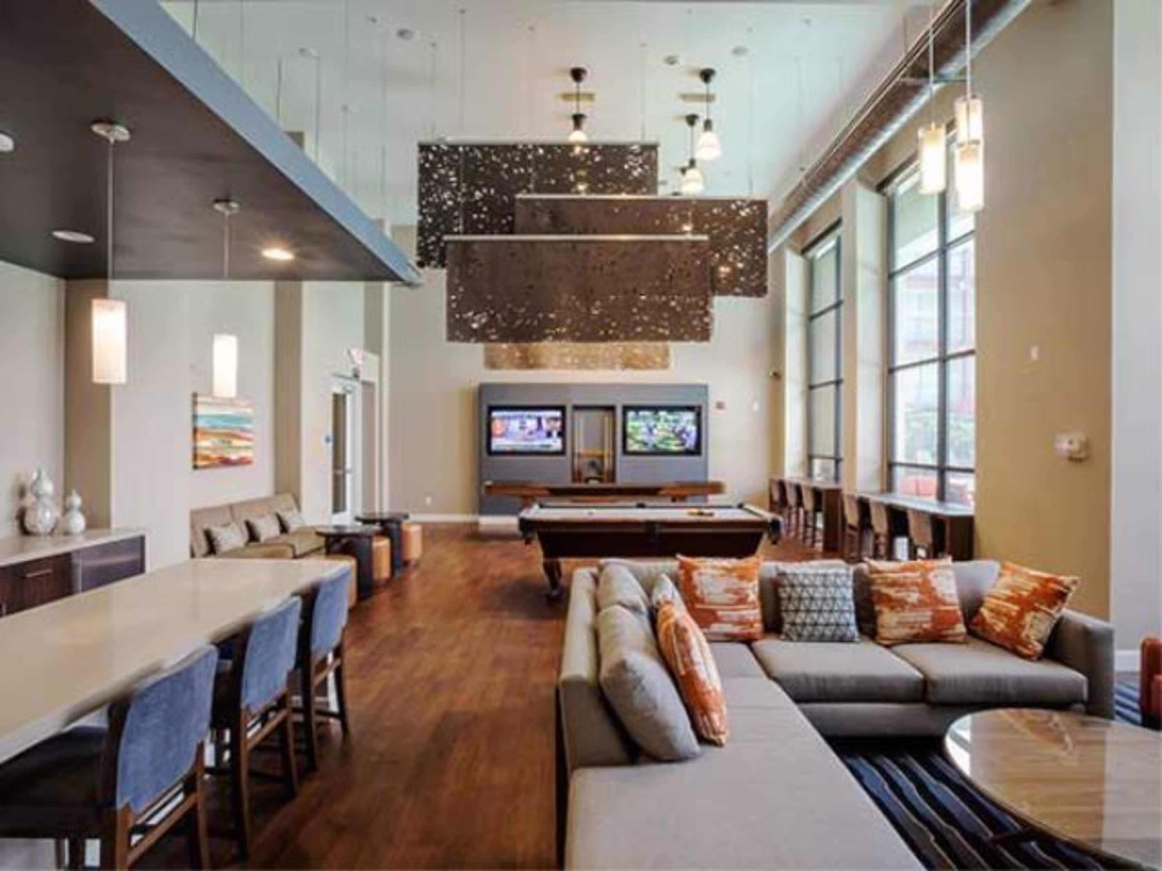 A spacious lounge area with a pool table, comfortable seating, and large windows bringing in natural light.