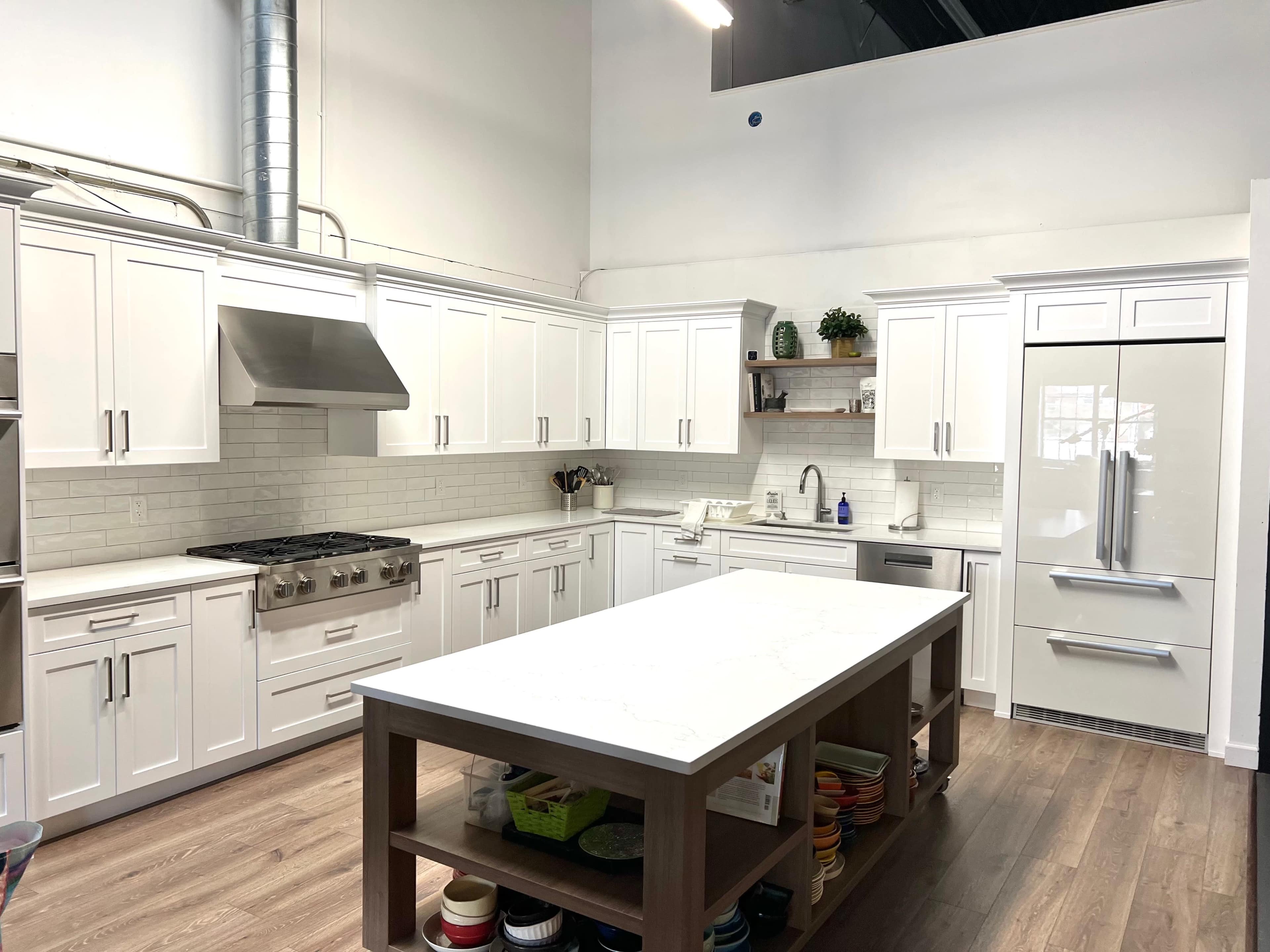 A modern kitchen with white cabinetry, stainless steel appliances, and a large central island.