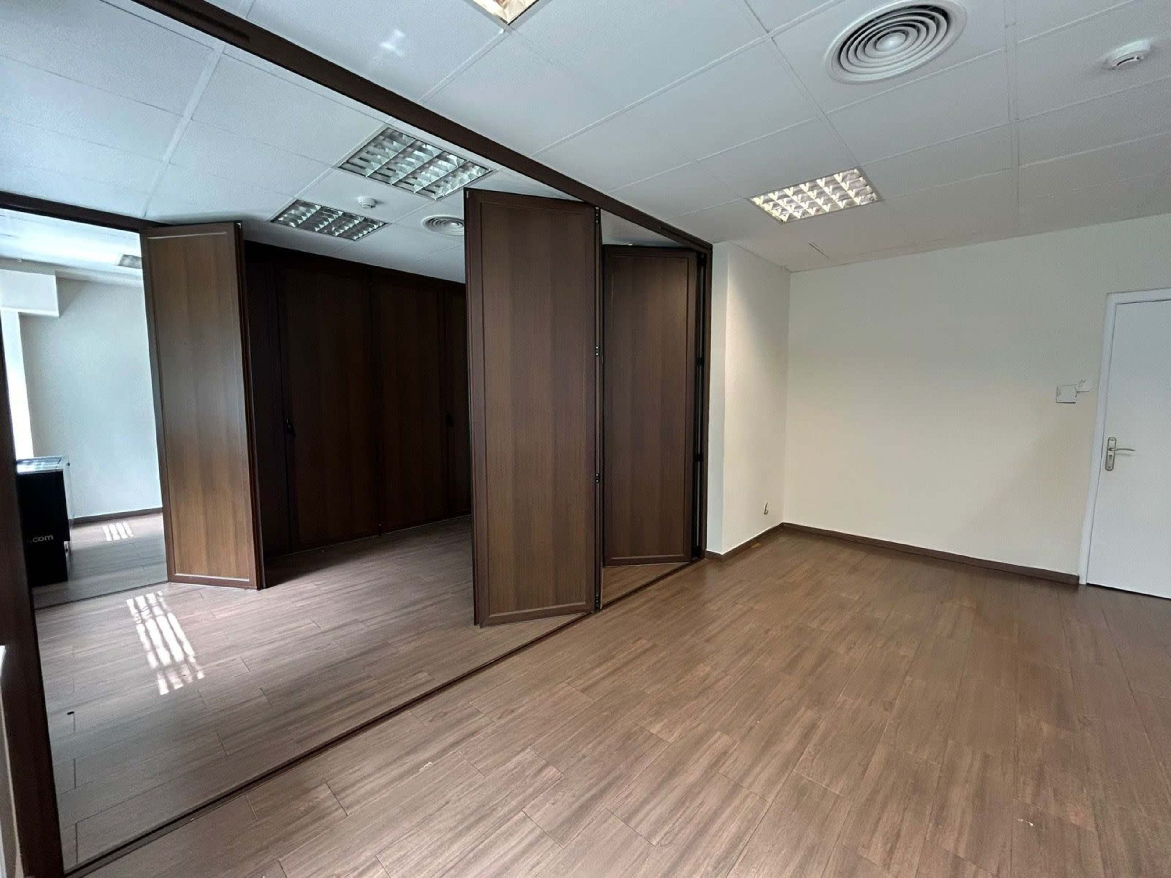 The image shows an office space with wooden cabinets and a light-toned floor.