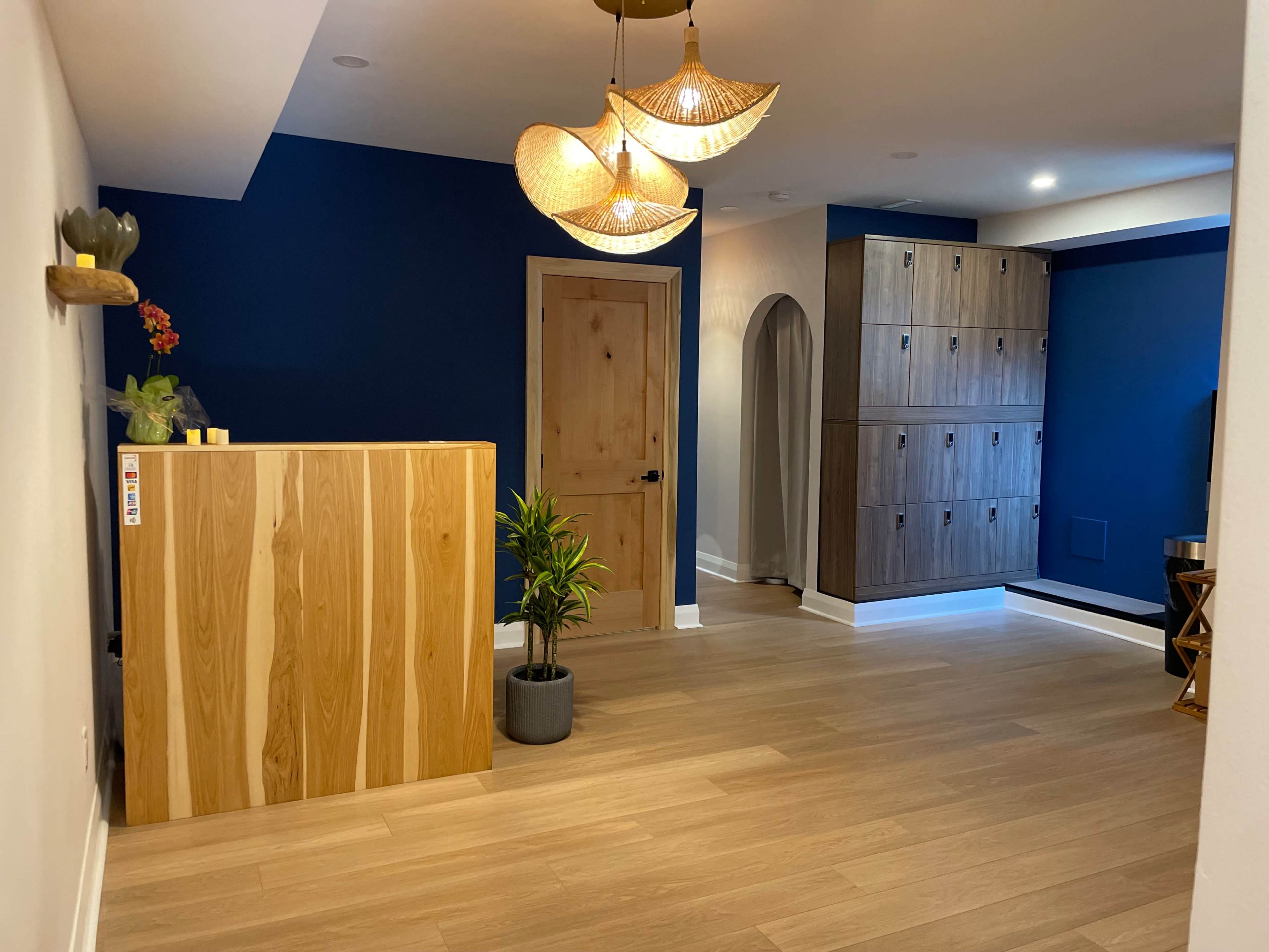 A spacious room featuring a wooden reception desk, a blue accent wall, and a set of cabinets on the right.