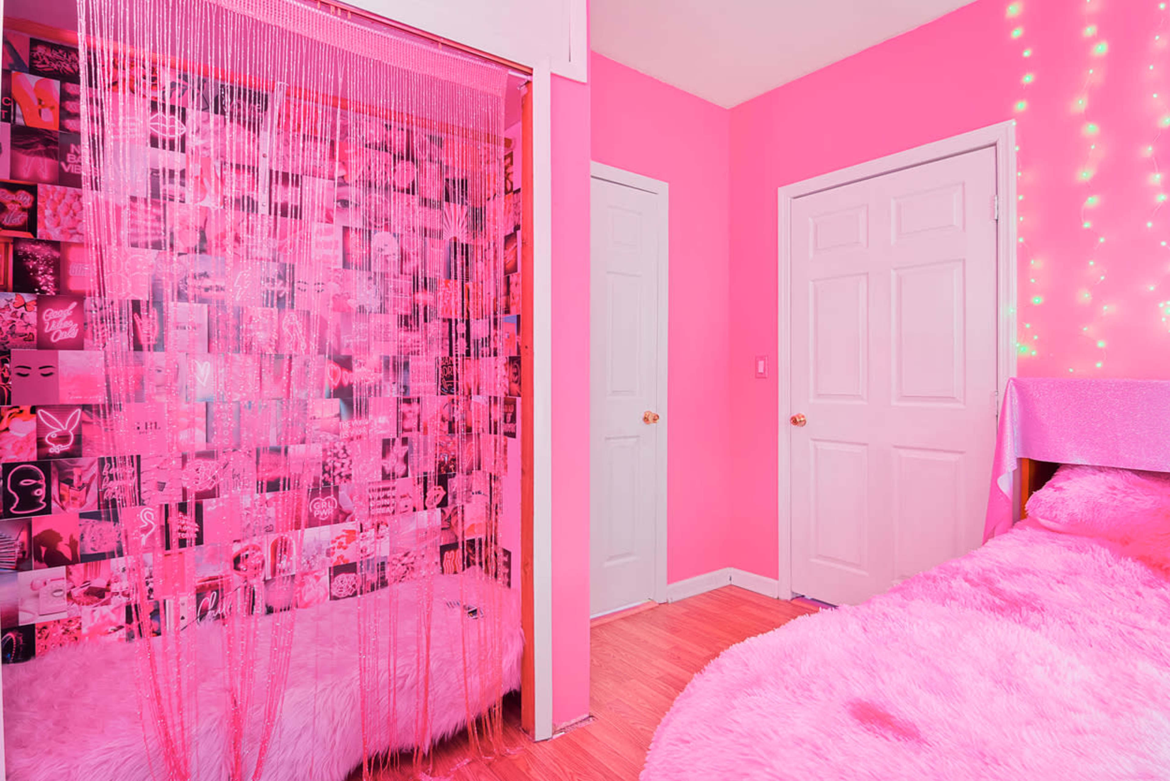 A bright pink bedroom featuring a beaded curtain, a photo collage wall, and a cozy bed with fluffy bedding.