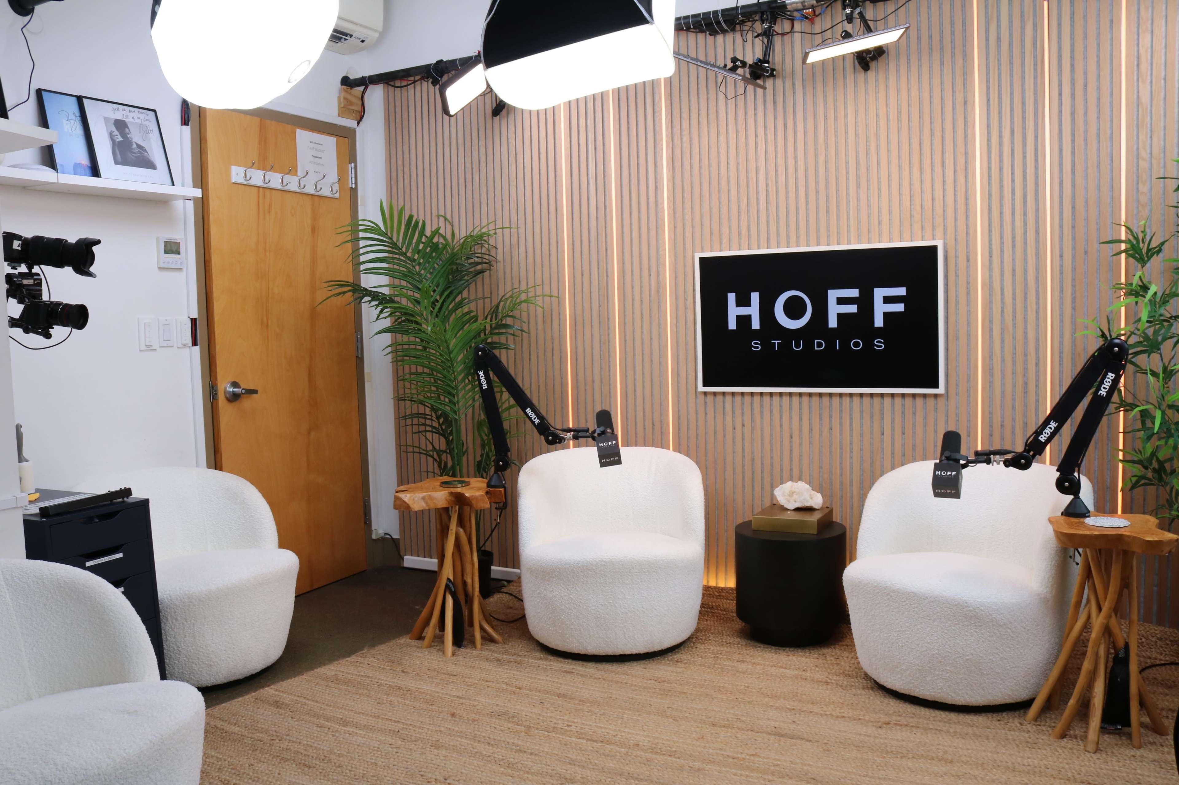 The image depicts a modern studio setting with two white chairs, a small black table, and a backdrop featuring the sign "HOFF STUDIOS."