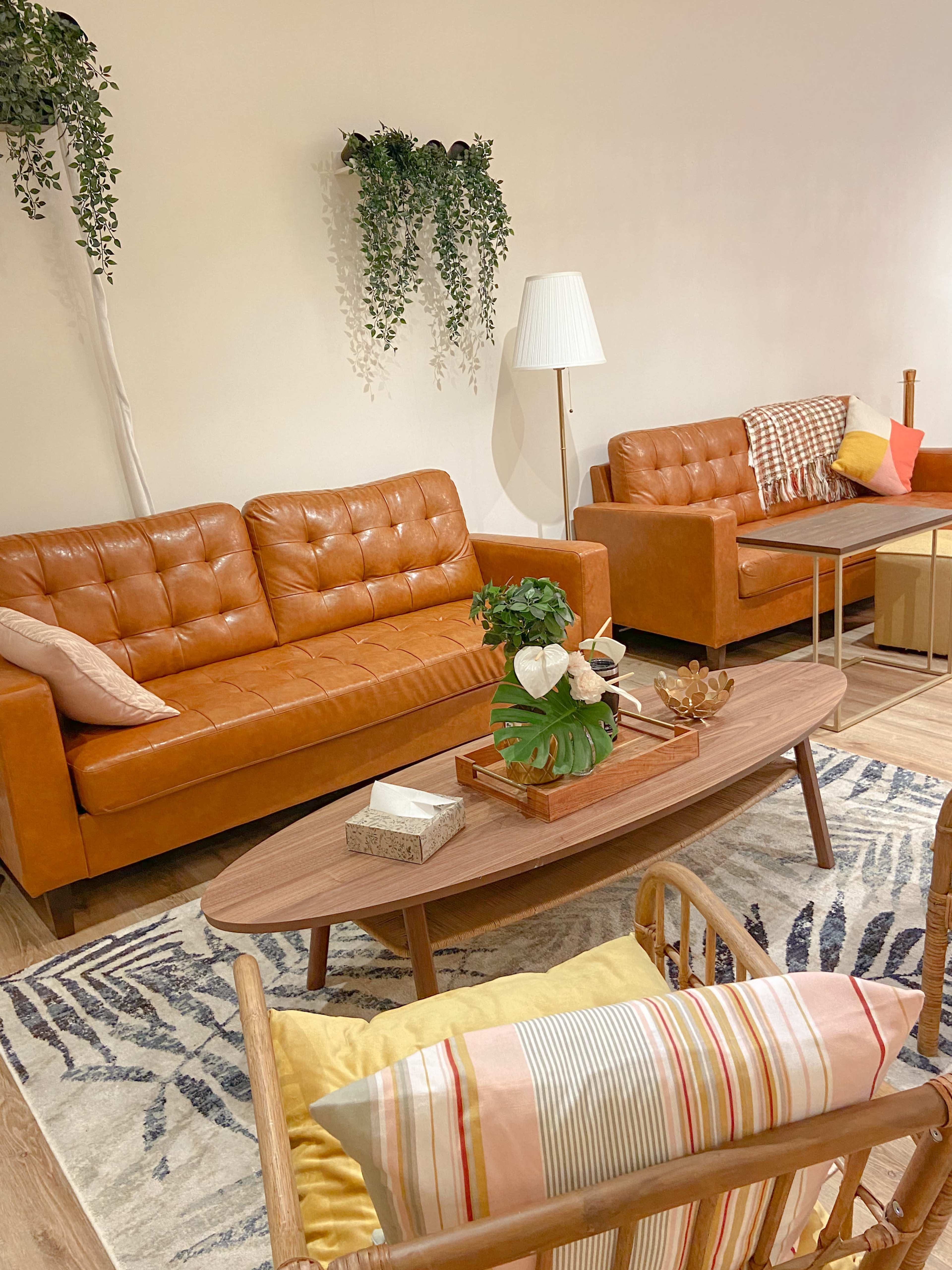 A cozy living room with two brown leather sofas, a wooden coffee table, and a patterned rug.
