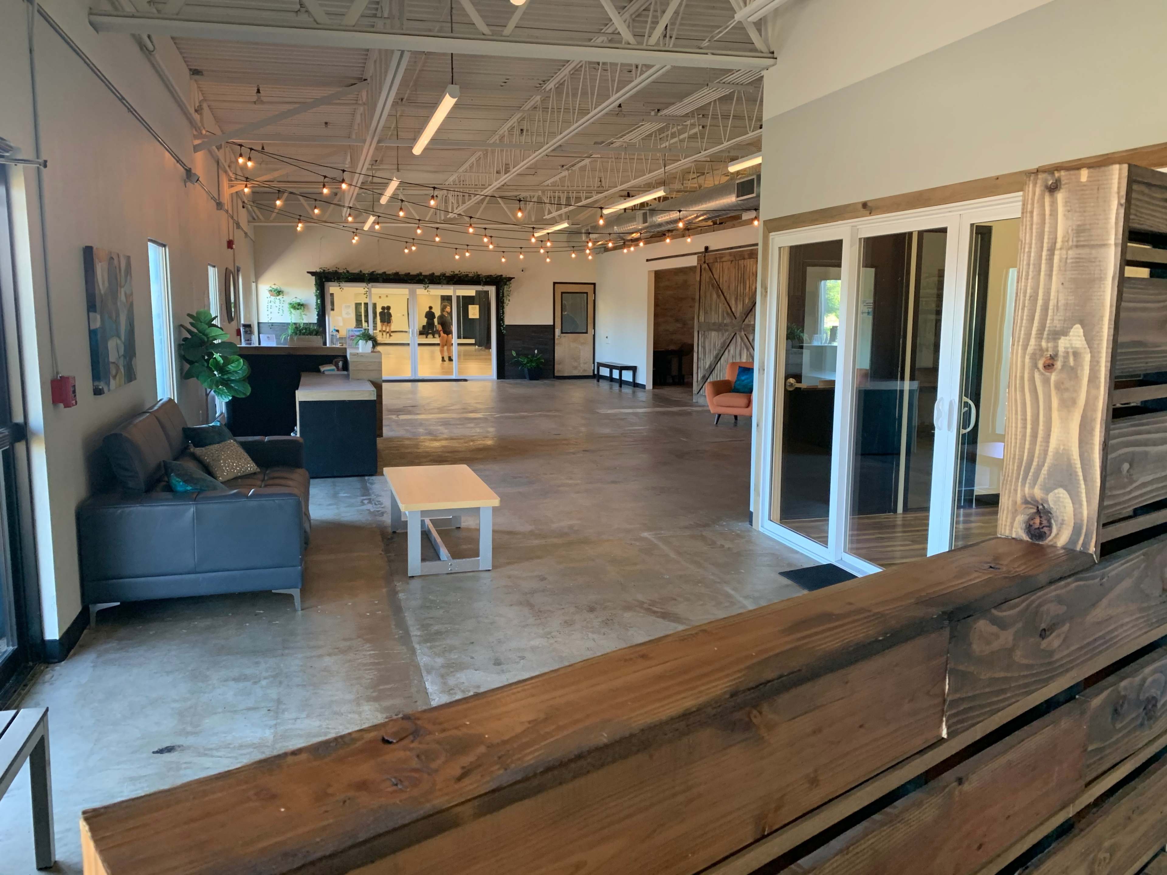 A spacious indoor area with a seating area, large windows, and decorative lighting.
