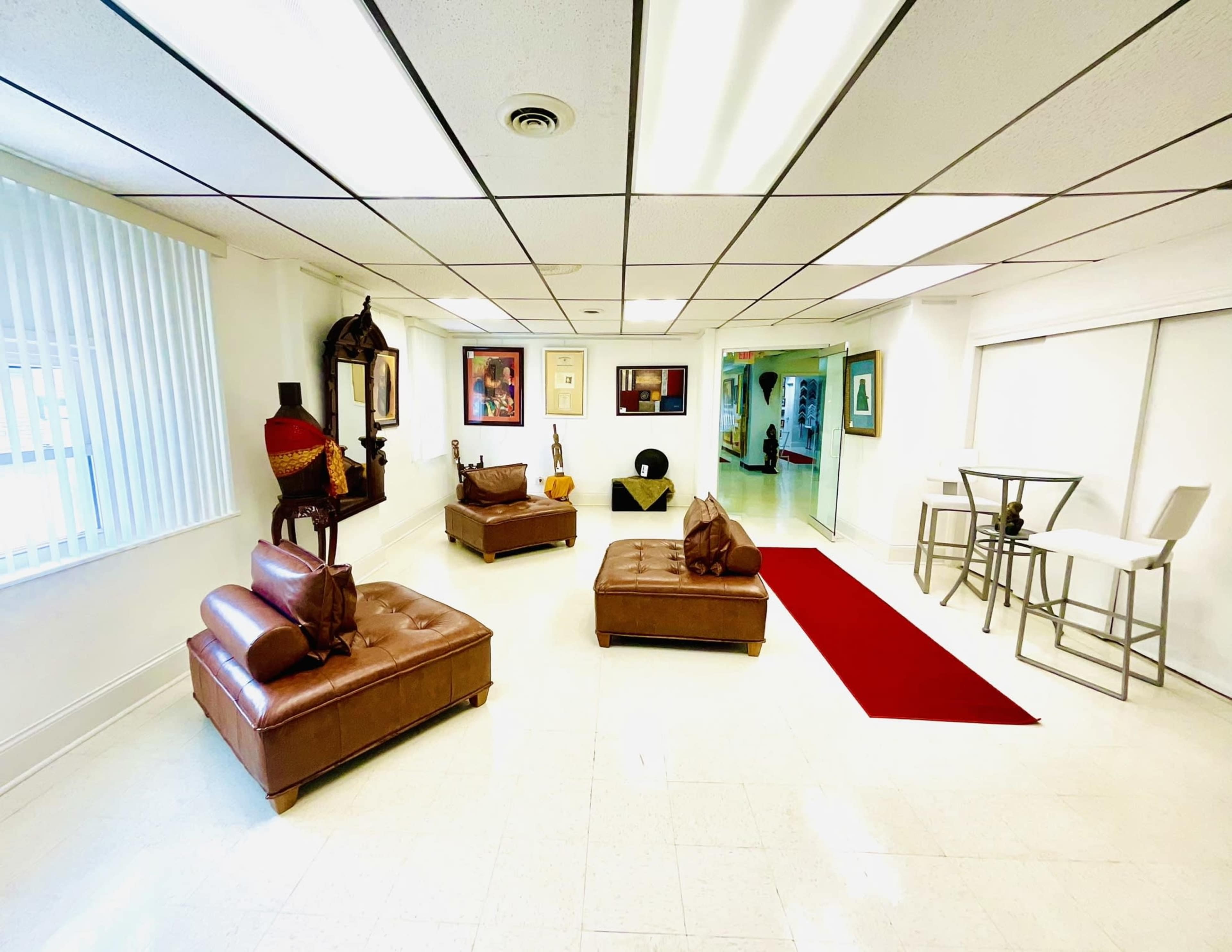A spacious room with two brown leather sofas, a red area rug, and a small dining table with white chairs.