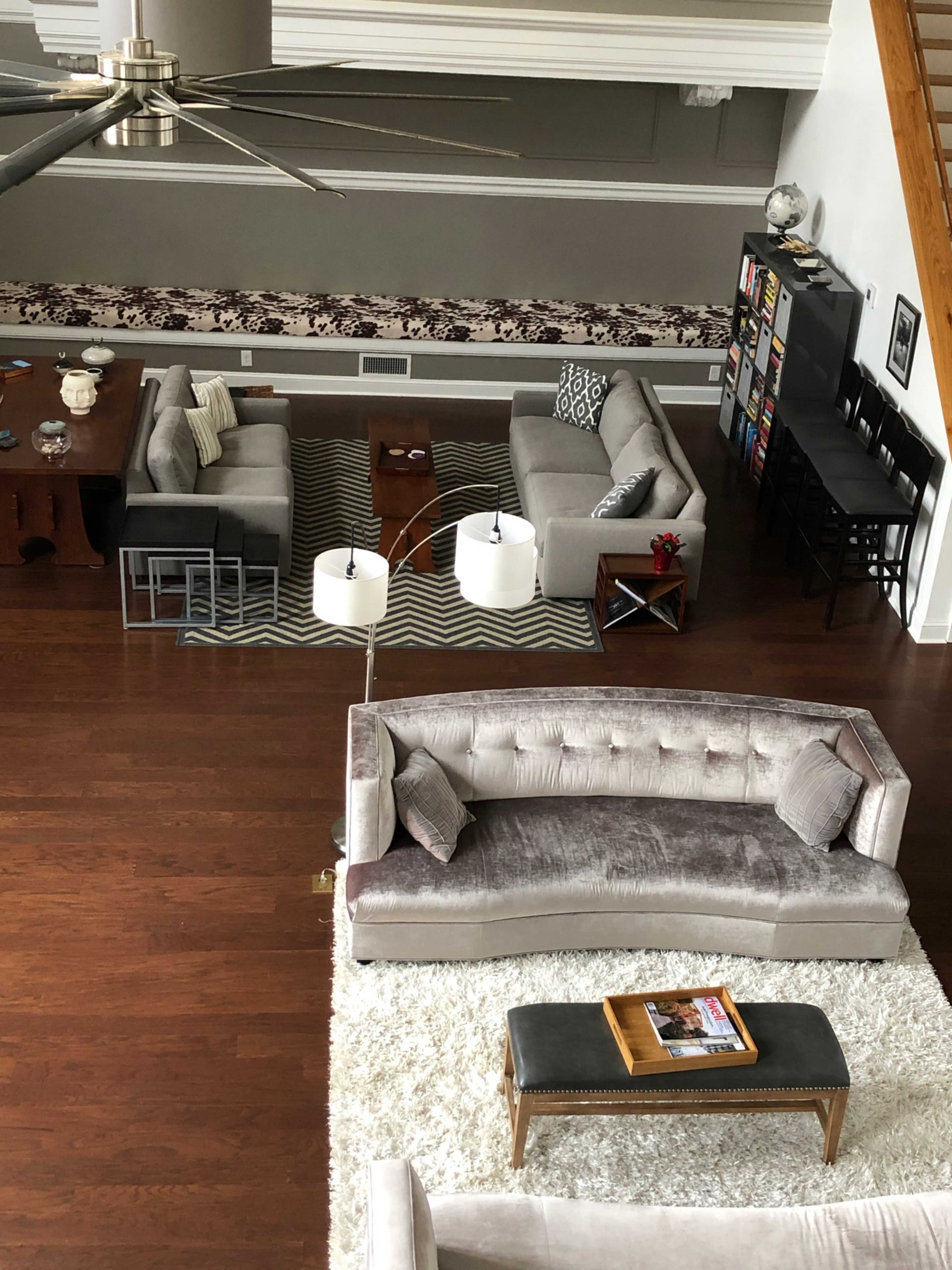 A spacious living room with several seating areas, including a large sectional sofa, coffee tables, and a bookcase.