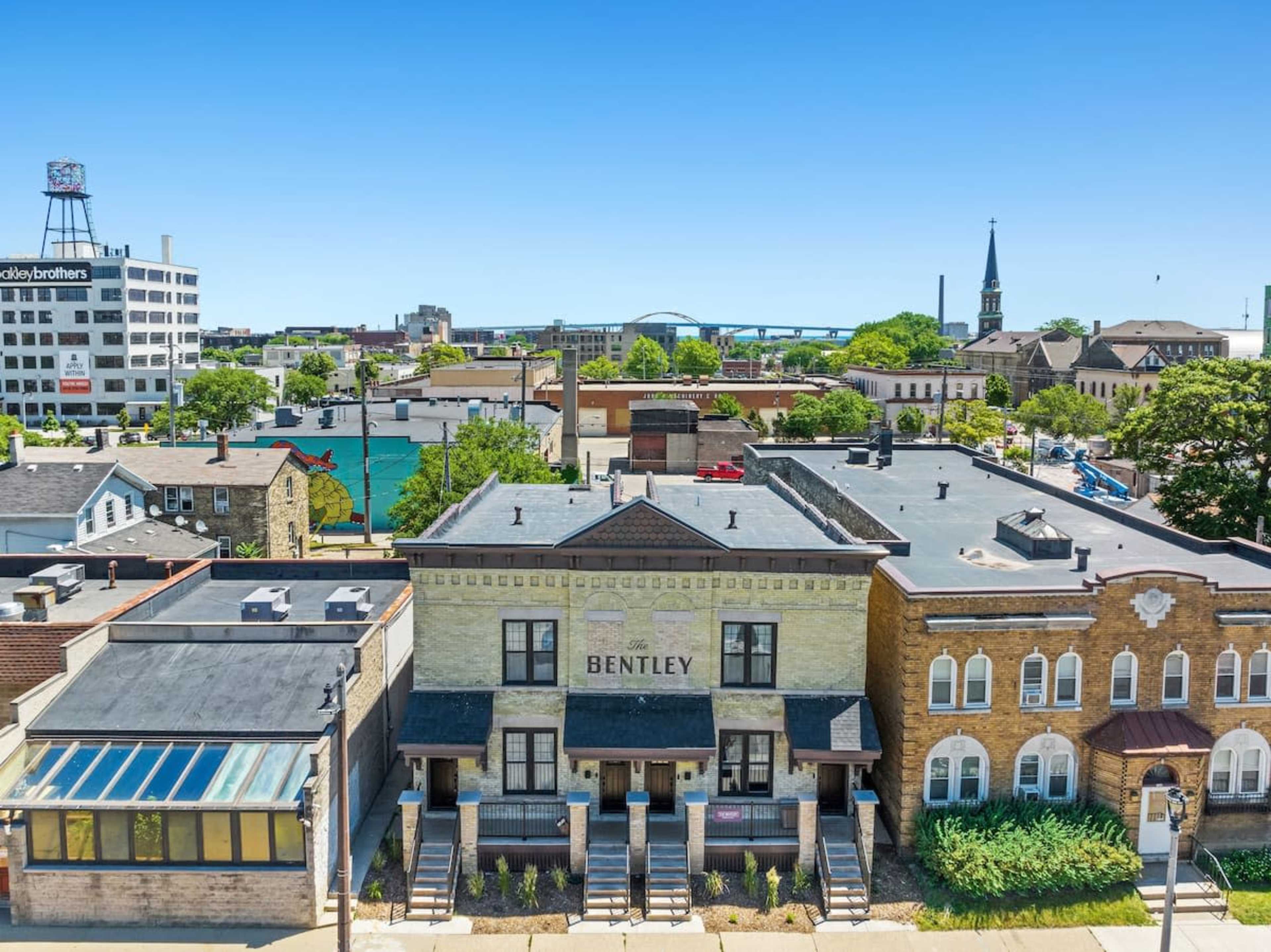 The image shows a view of a cityscape featuring the Bentley building, several surrounding structures, and a prominent steeple in the background.