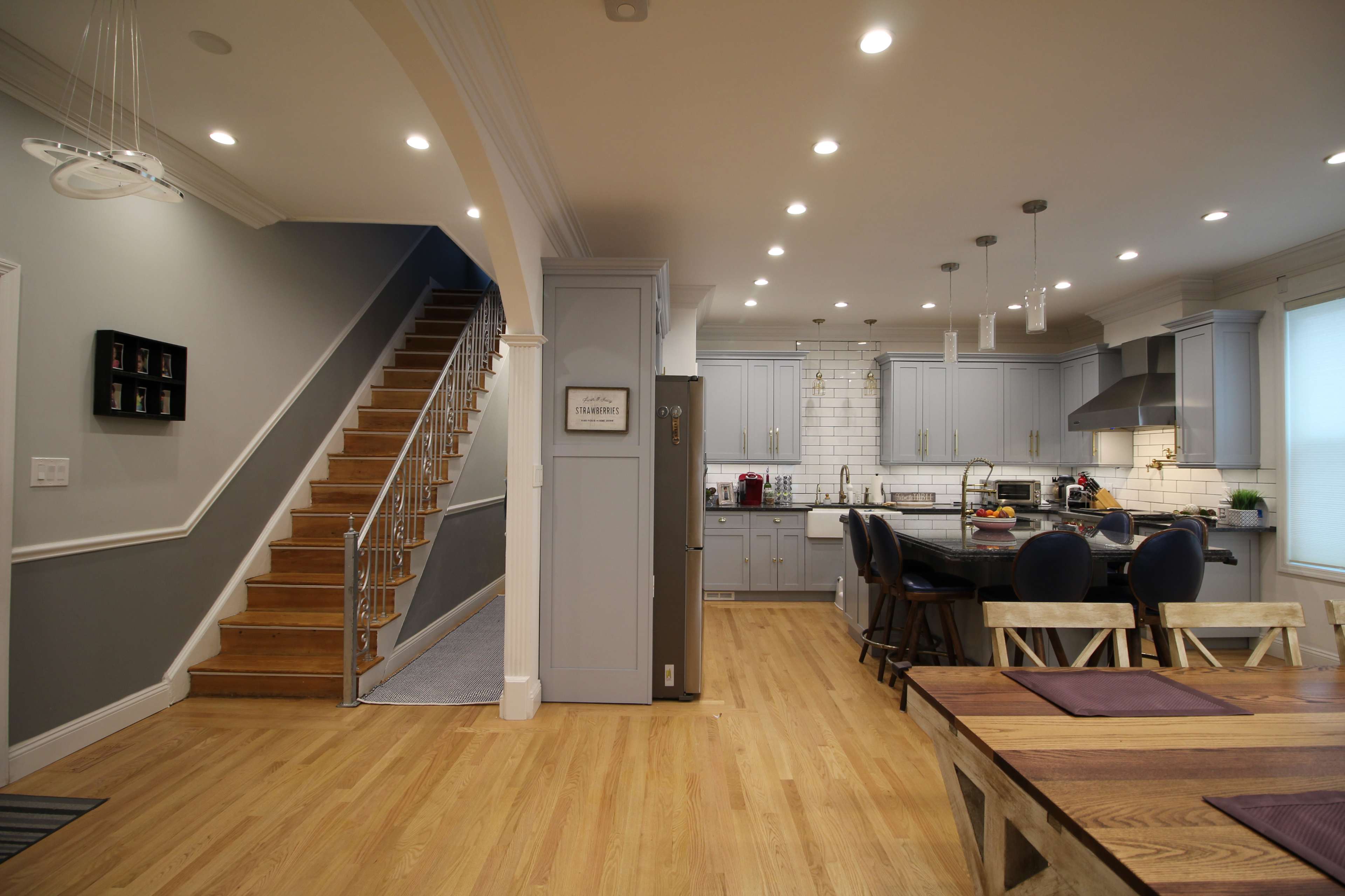 A modern open-concept living space featuring a kitchen, a dining area, and a staircase leading to an upper level.