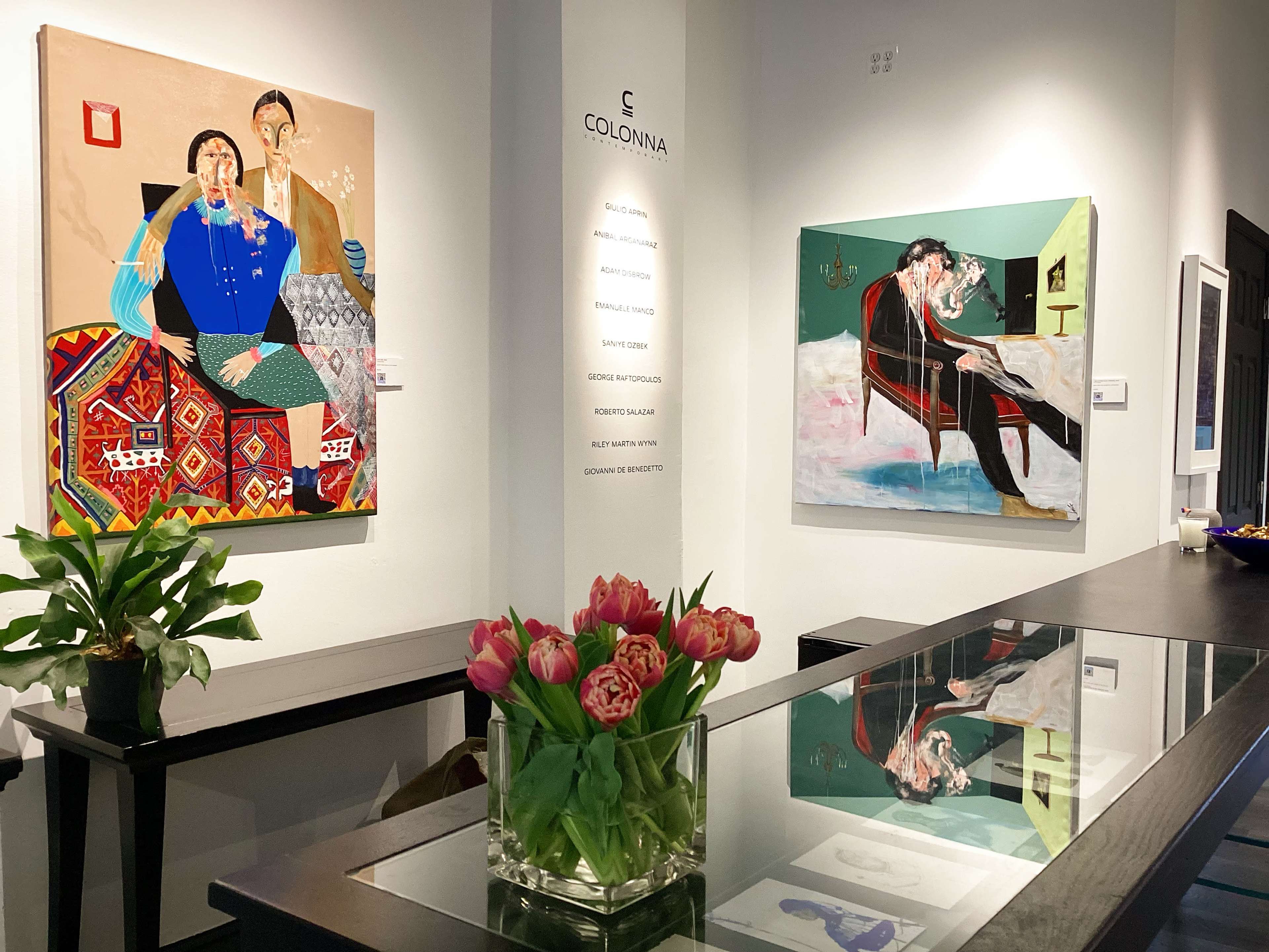 An art gallery interior featuring two large paintings on the walls and a table with a vase of tulips in the foreground.