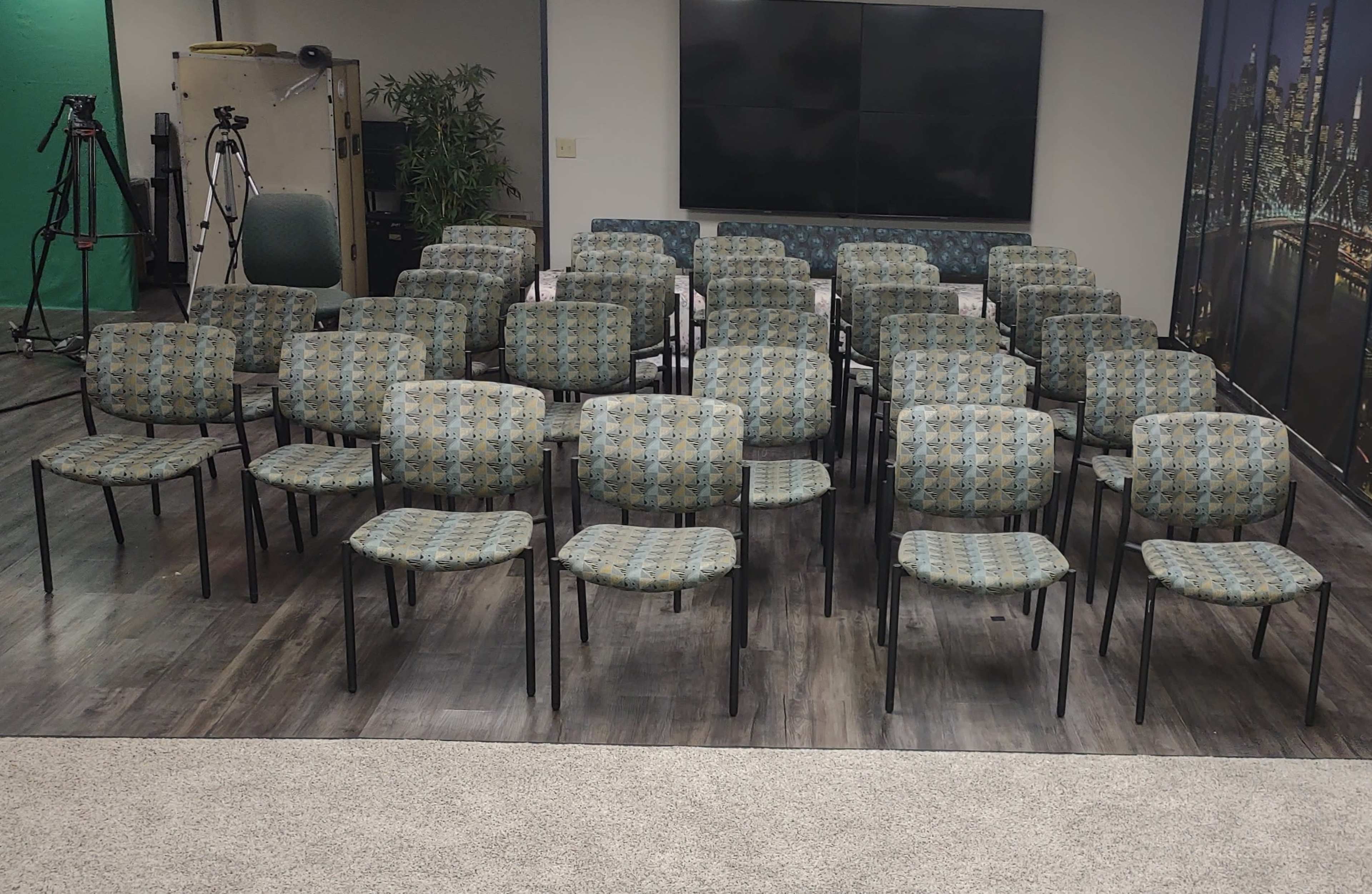 A room contains multiple rows of patterned chairs arranged in a neat grid formation.