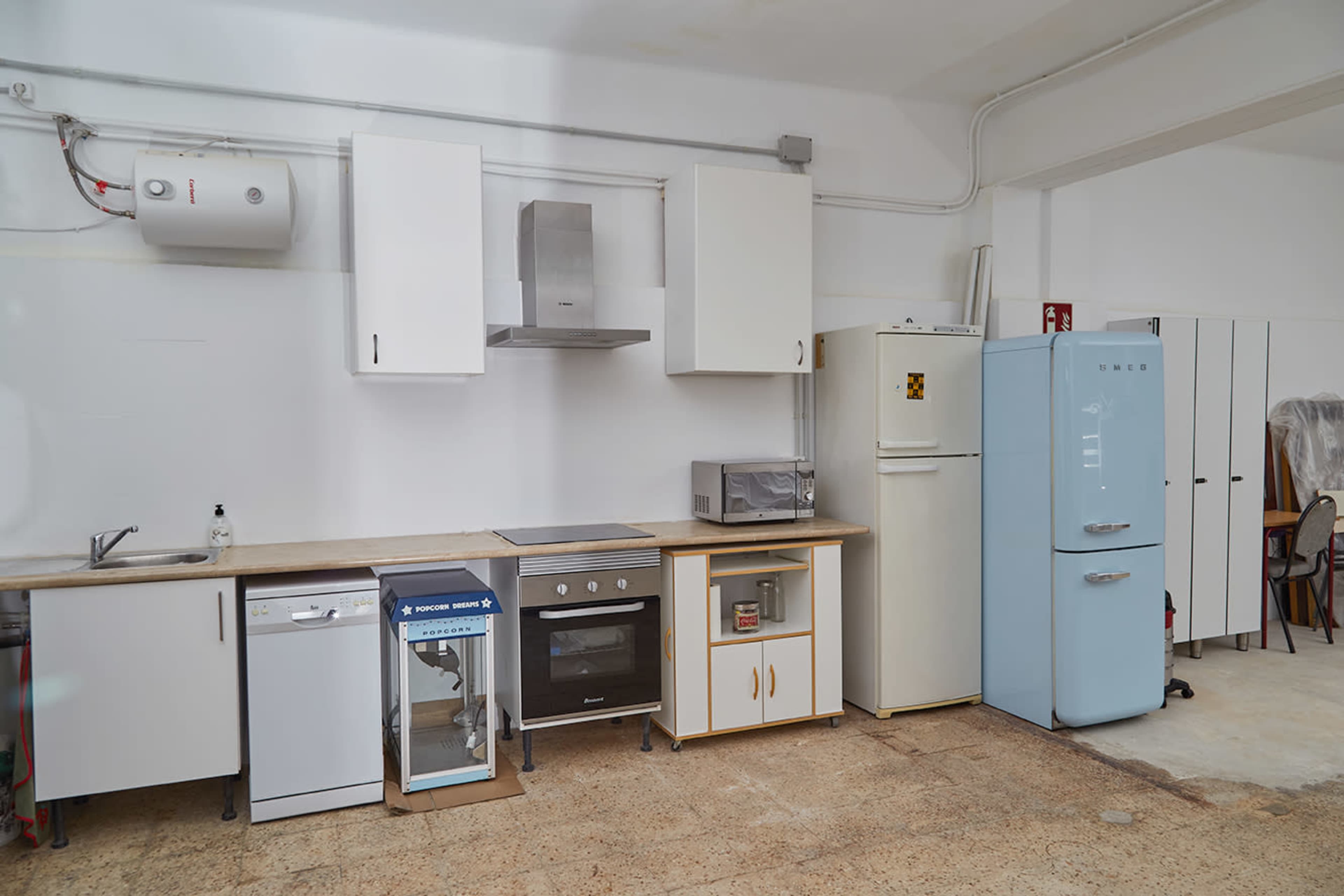 The image shows a clean kitchen with a refrigerator, stove, microwave, and various cabinets arranged along the wall.