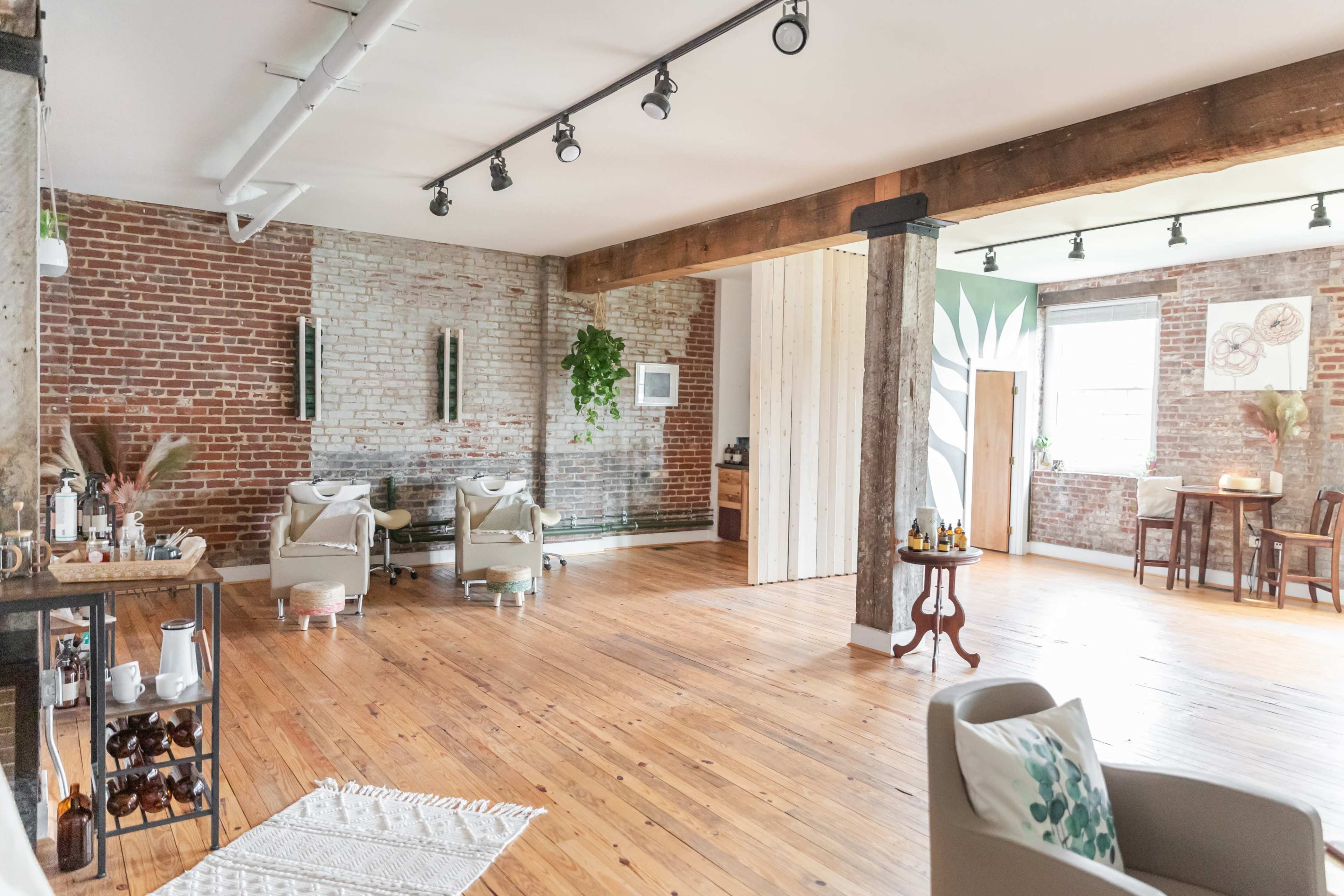 A spacious interior with exposed brick walls, wooden floors, and cozy furniture arranged in a wellness studio.