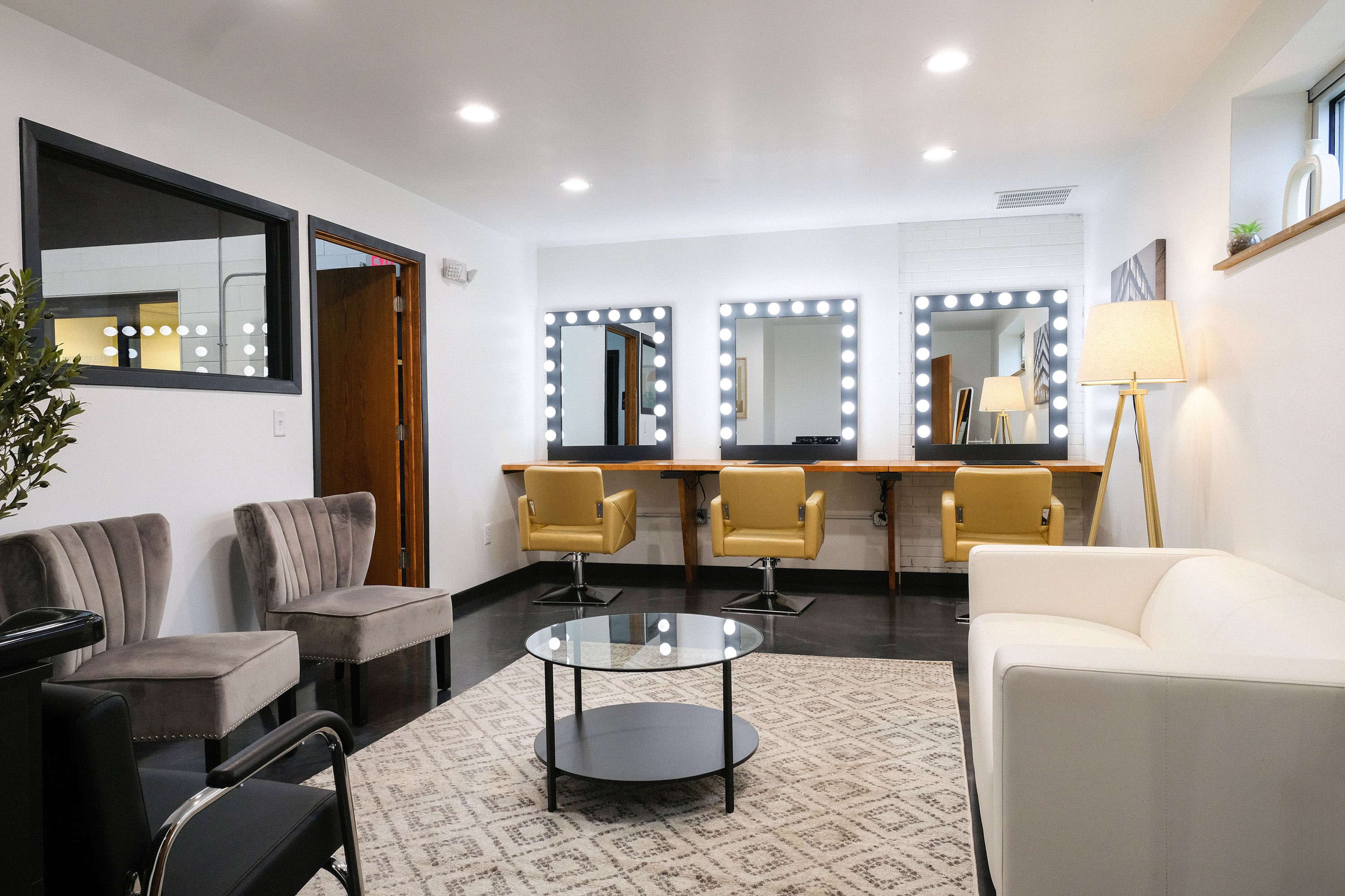 A modern dressing room with mirrors, bright lights, and various seating arrangements.