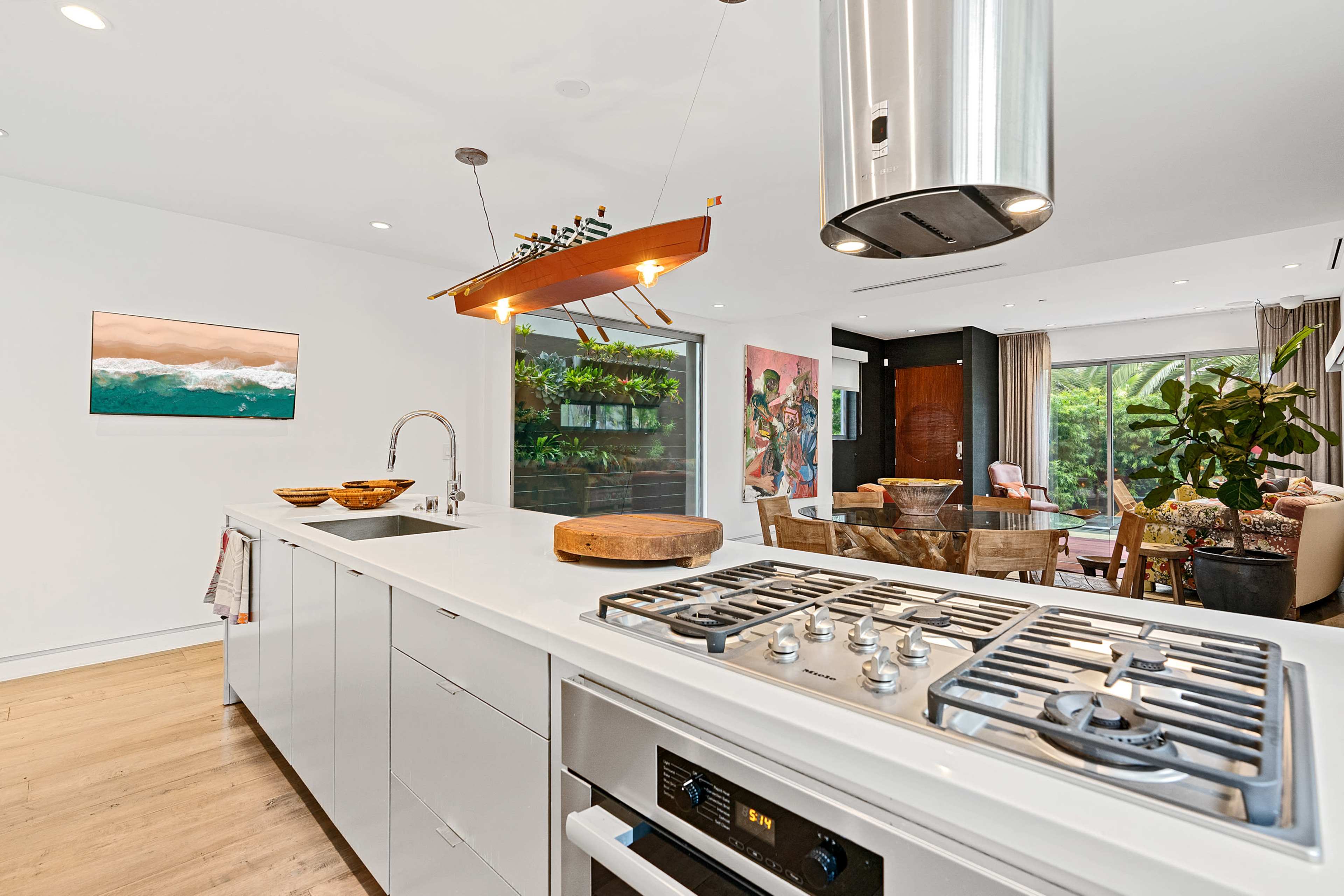 A modern kitchen with a white countertop, a gas stove, and a decorative boat-shaped light fixture above.