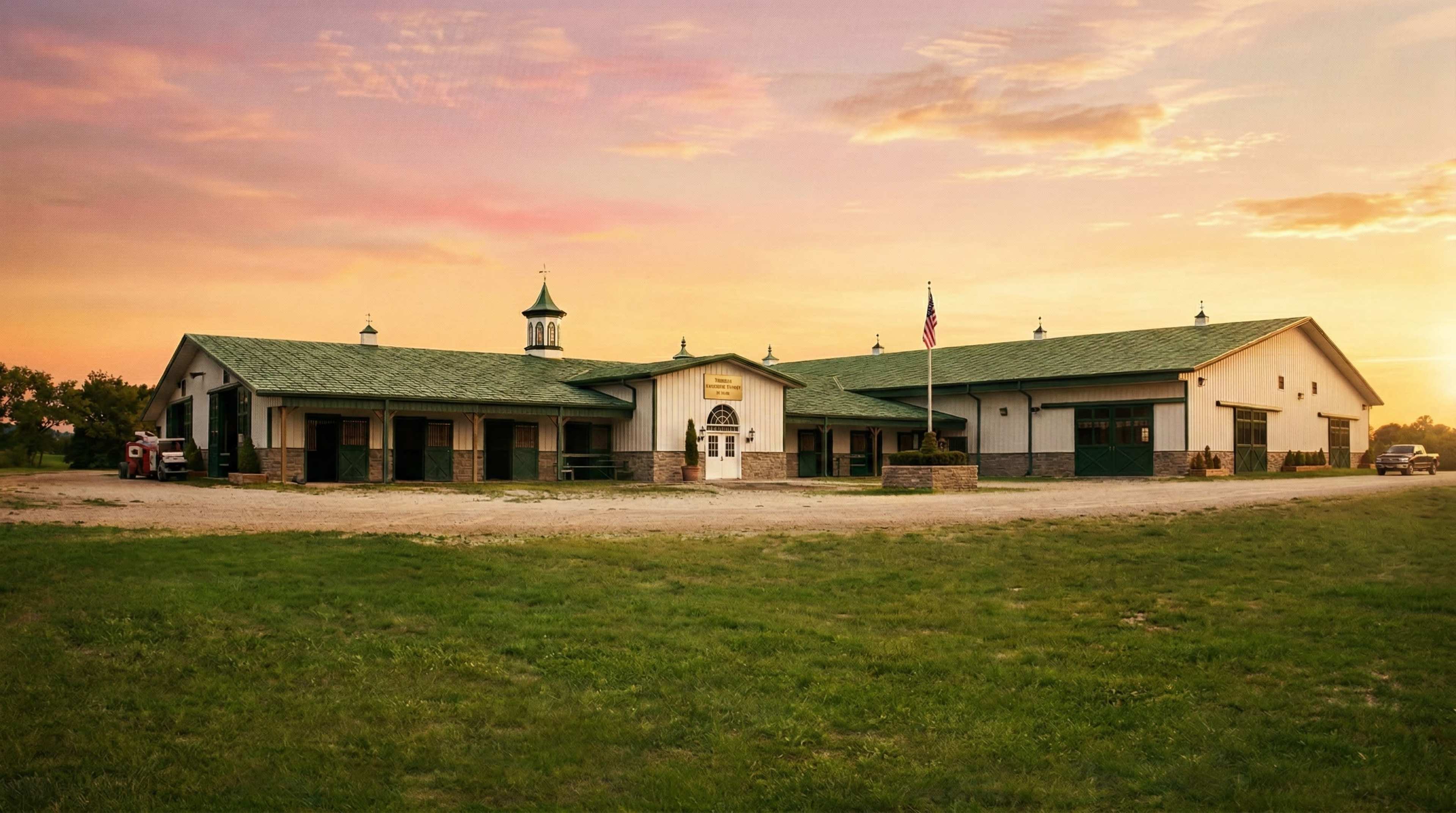 A large, decorative agricultural building with a green roof and a flagpole stands against a sunset backdrop.