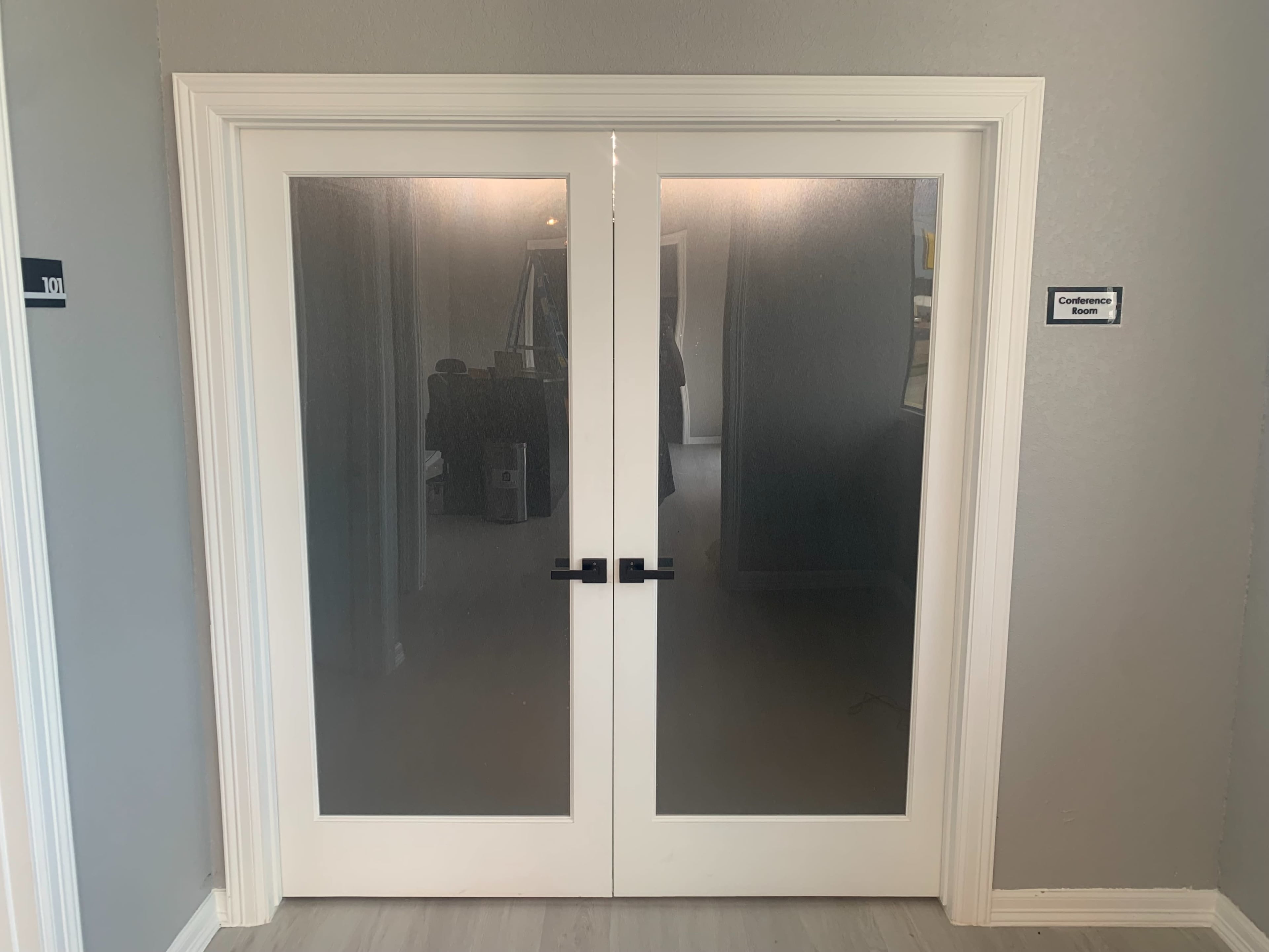 A set of double glass doors with black handles, leading to a room labeled "Conference Room."
