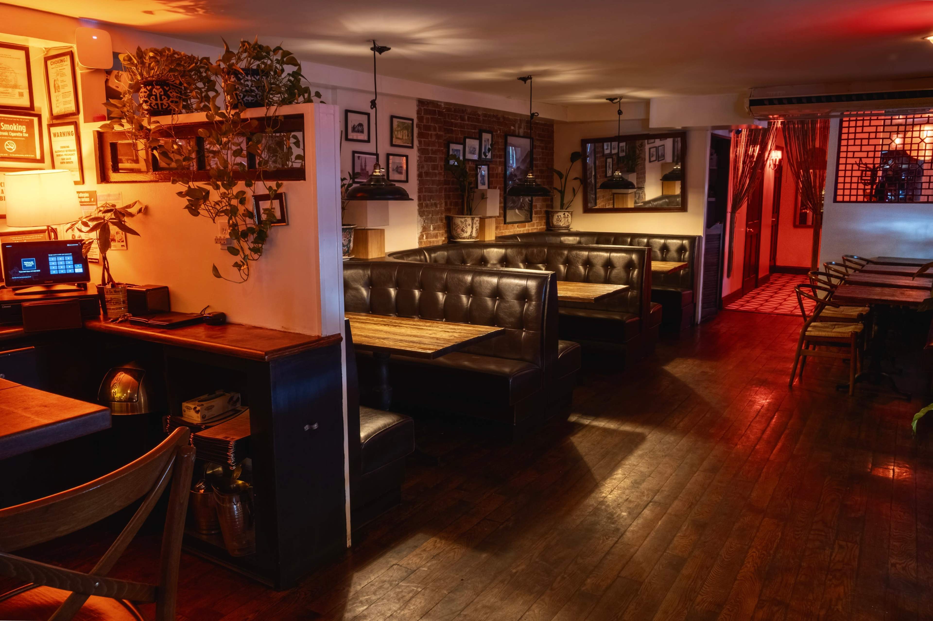 The image shows a cozy restaurant interior with wooden flooring, leather booths, and vintage decor along the walls.