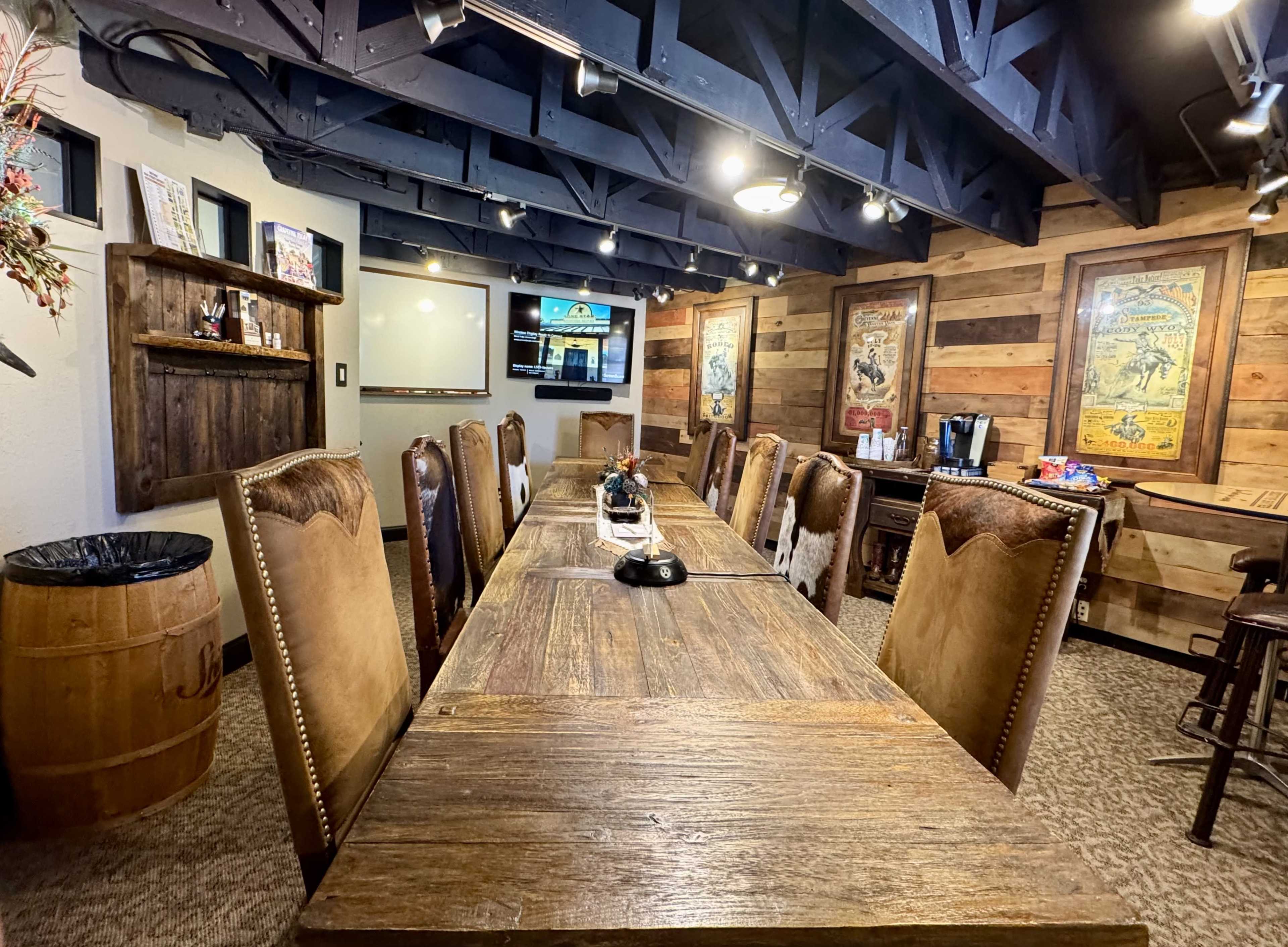 The image shows a rustic meeting room with a long wooden table surrounded by leather chairs, dim lighting, and wooden paneling on the walls.