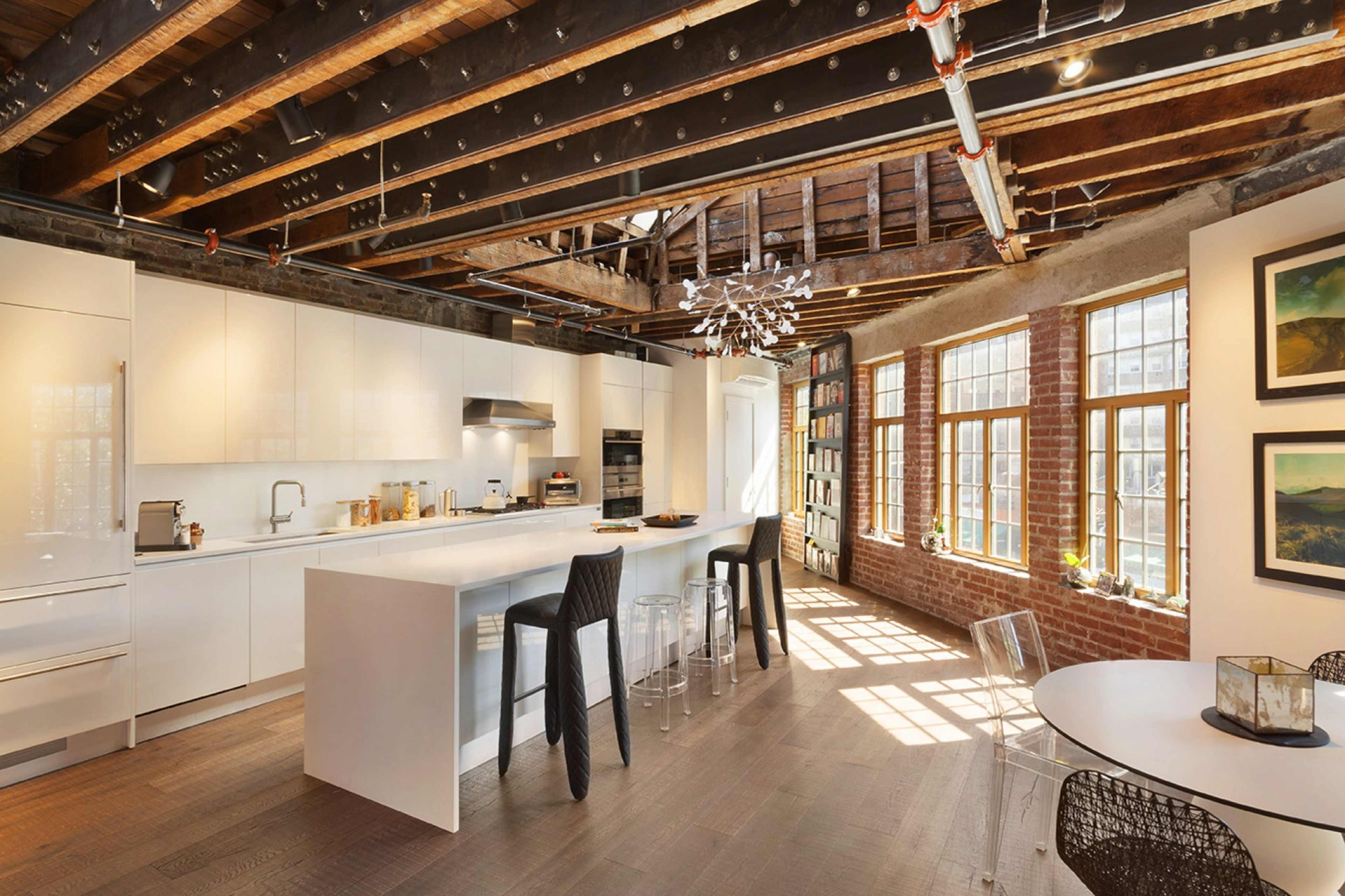 A modern kitchen with white cabinetry, a large island, and large windows that allow natural light to fill the space.