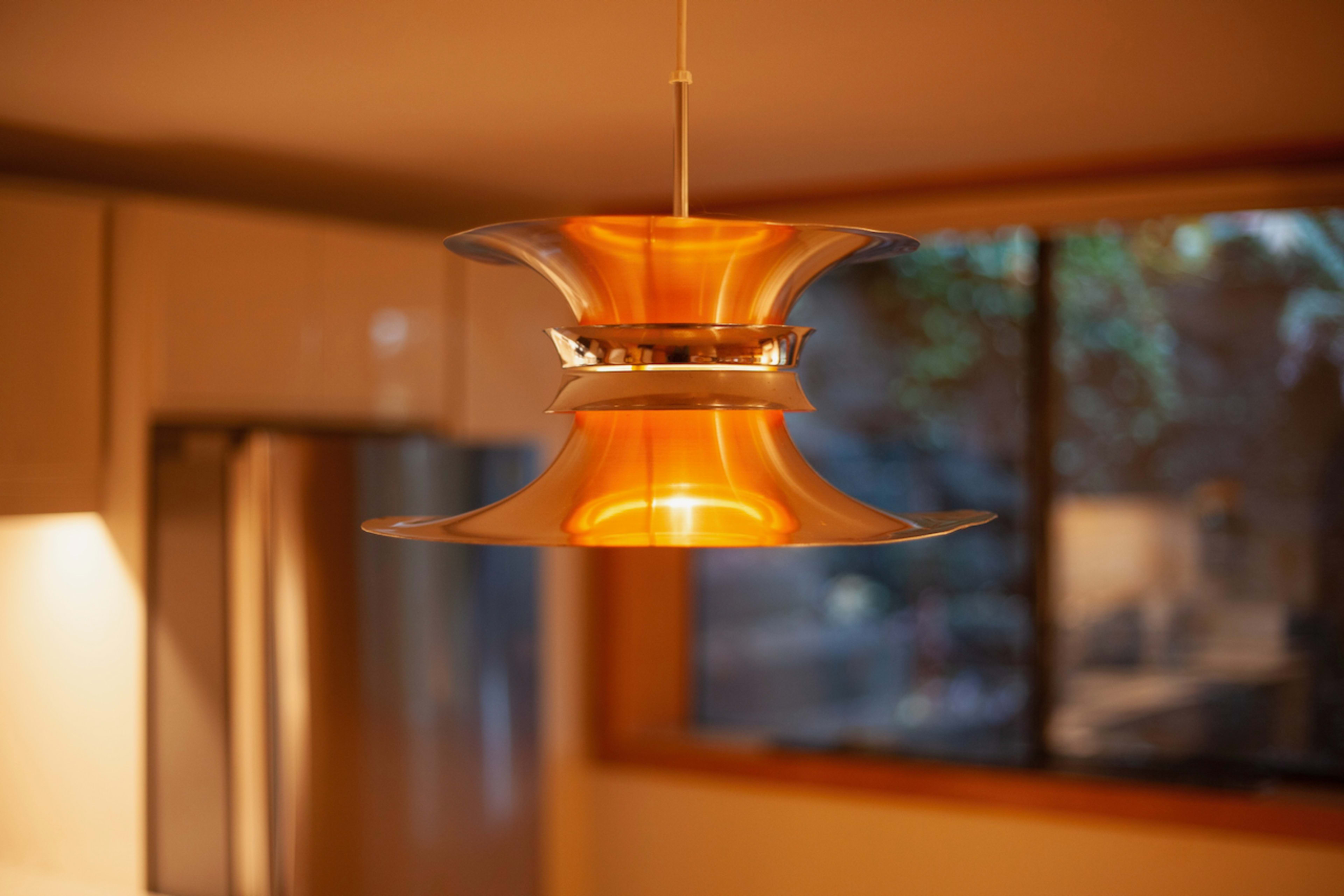A modern pendant light with a fluid, sculptural design hangs above a kitchen space.