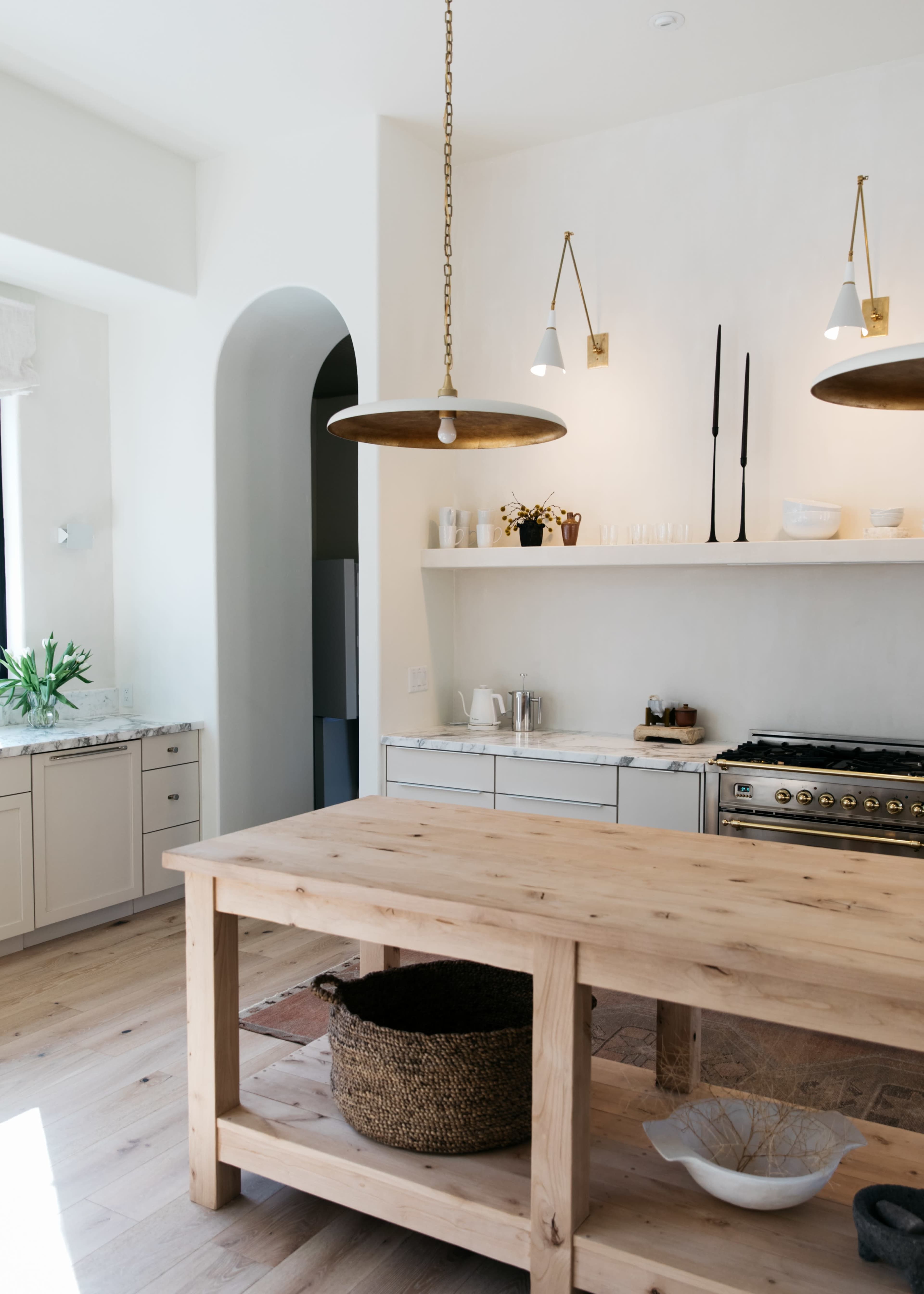 A modern kitchen with a wooden island, pendant lights, and open shelving above the countertop.