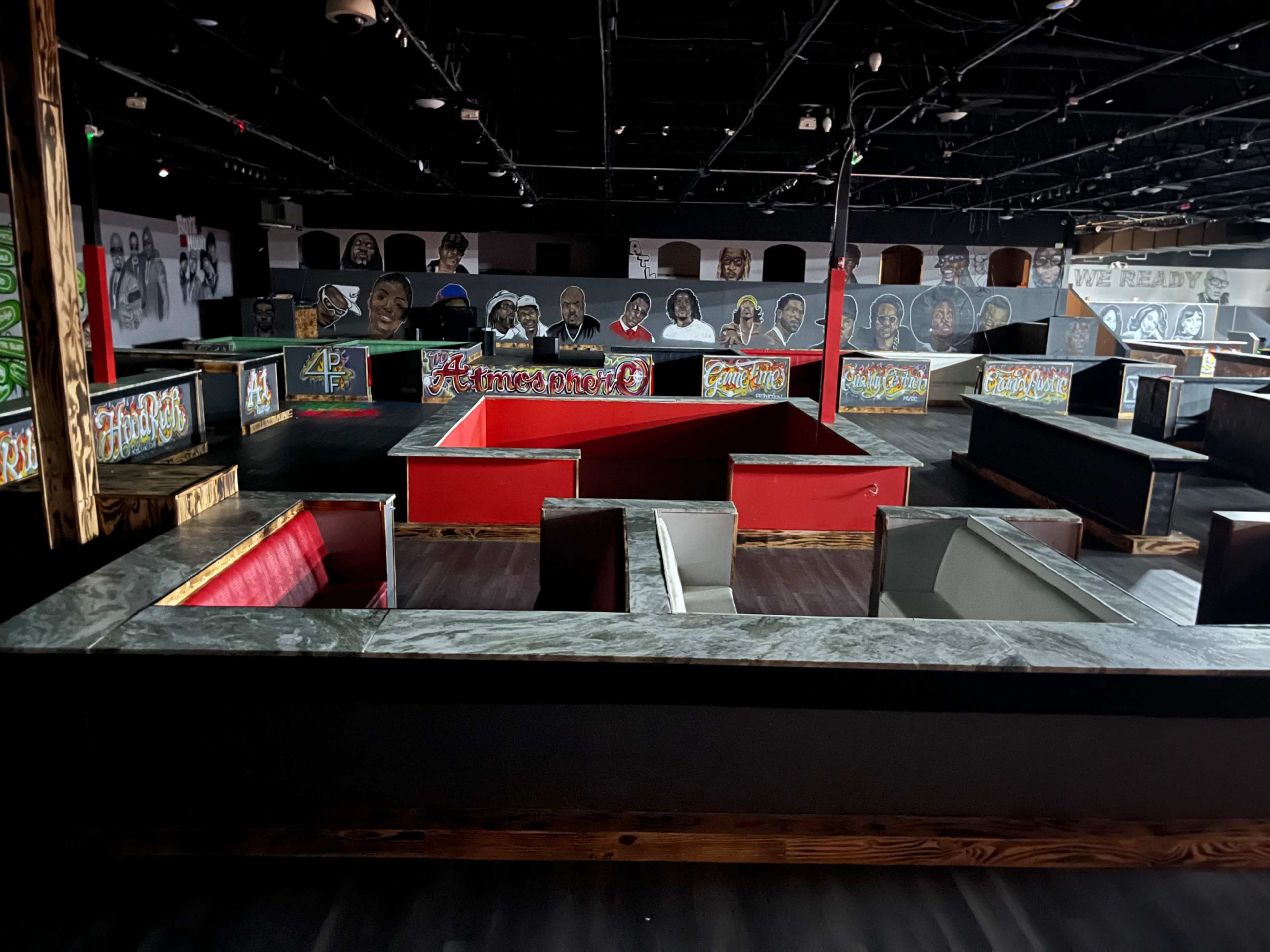 The image shows a large indoor space featuring a maze-like structure with various painted walls and graffiti art.