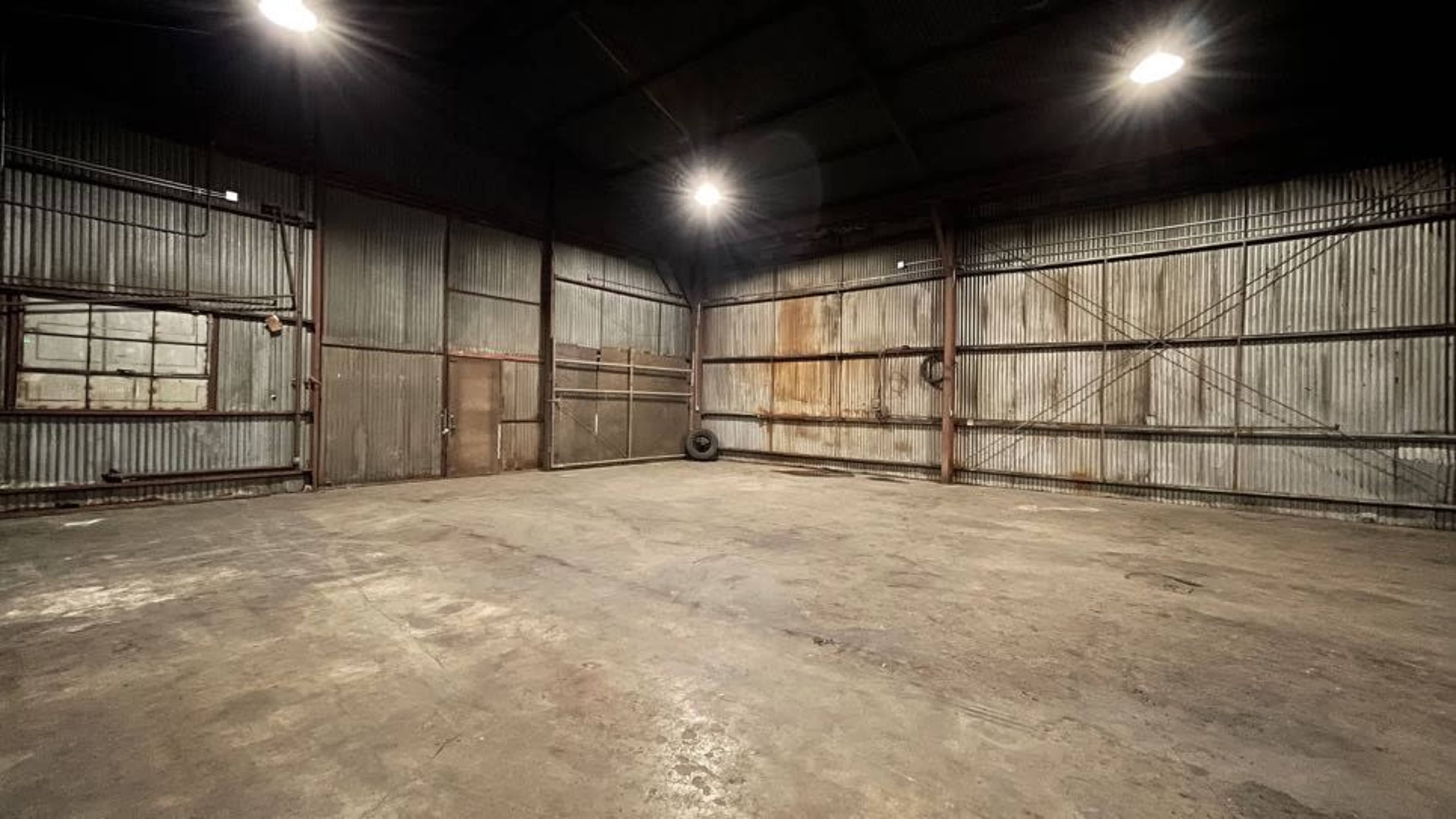 An empty industrial warehouse with corrugated metal walls and a concrete floor.