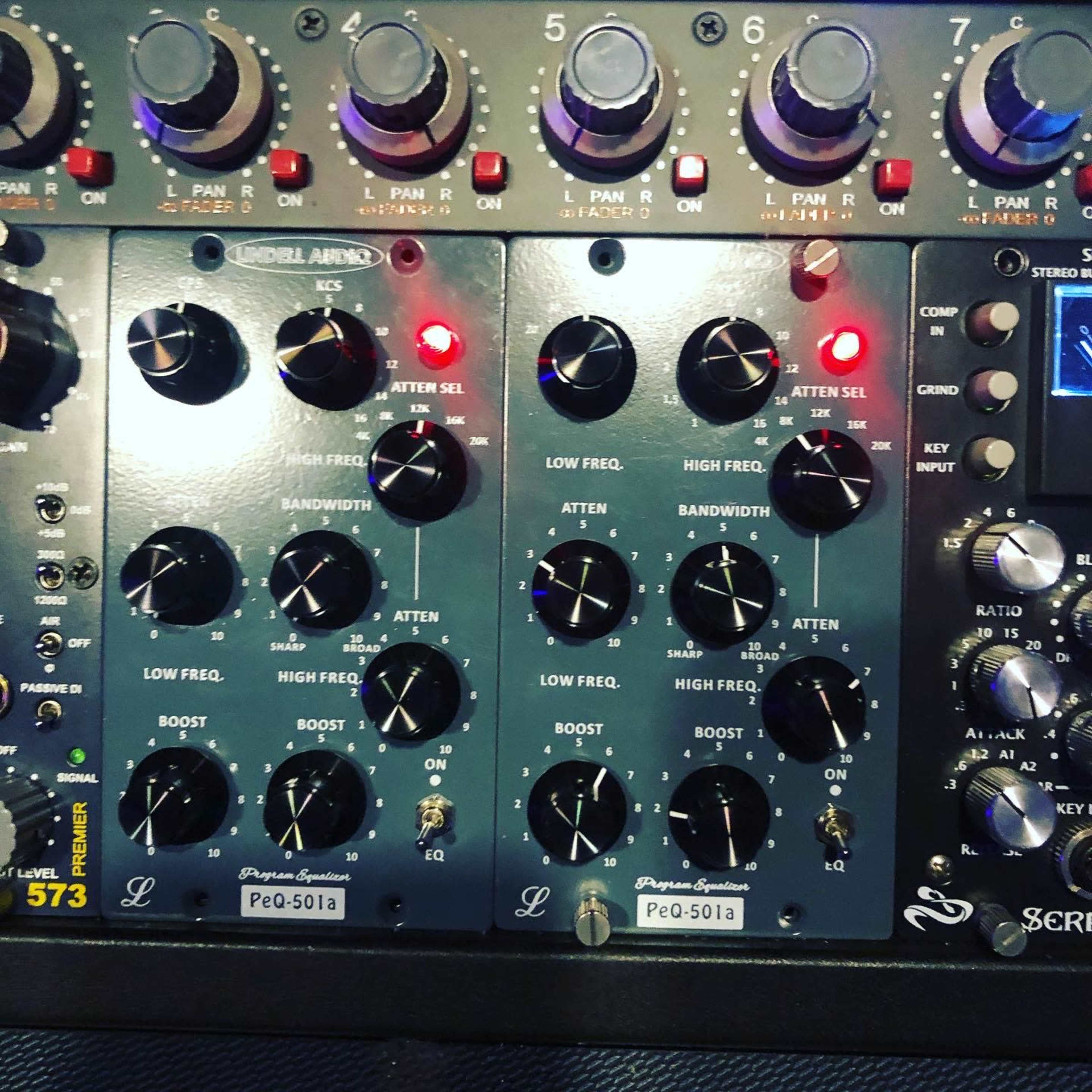 An audio mixing console with various knobs and switches, including controls for frequency, boost, and attenuation.