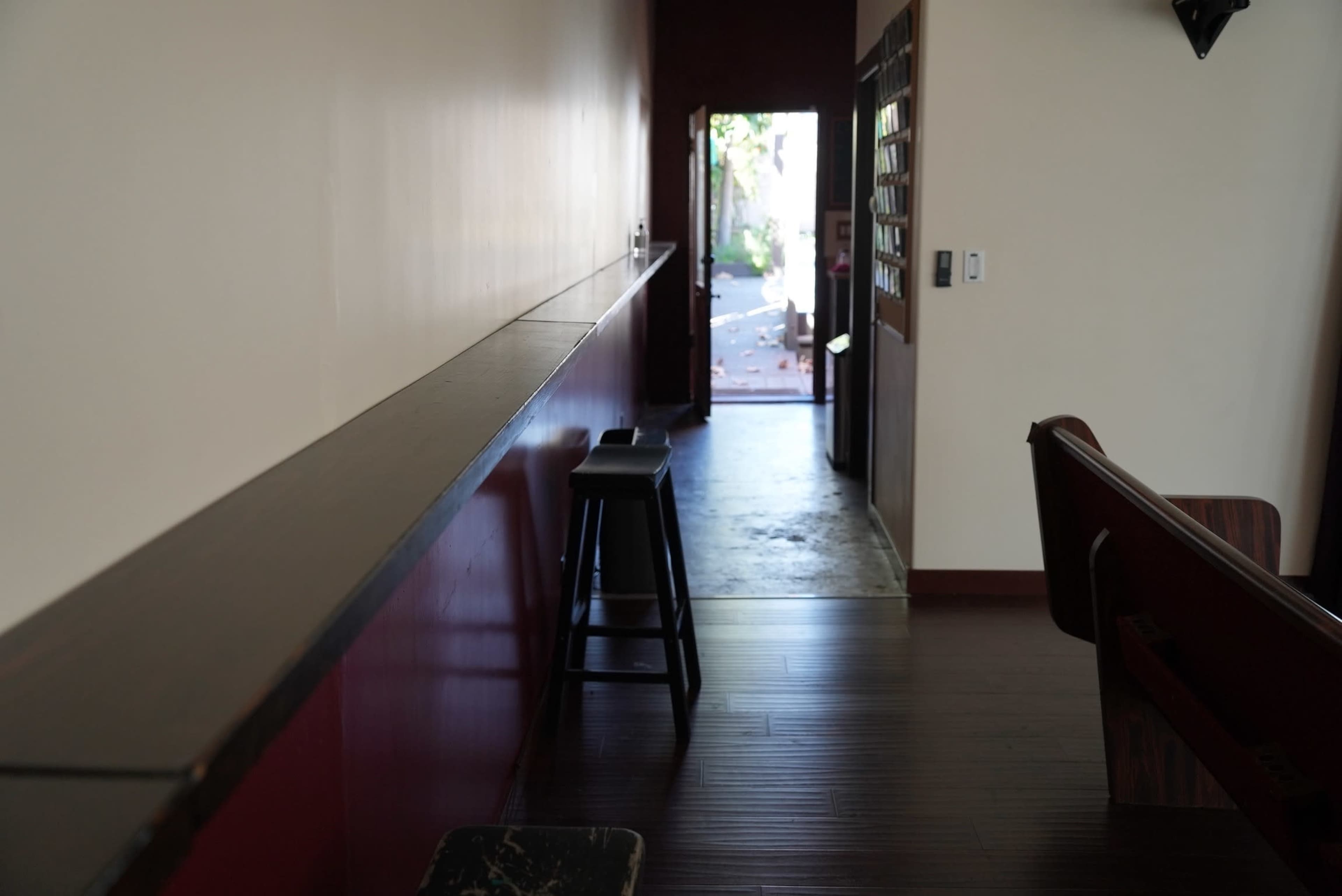 A long hallway features a bar-like ledge on one side, with a view of an outdoor area through an open door at the end.
