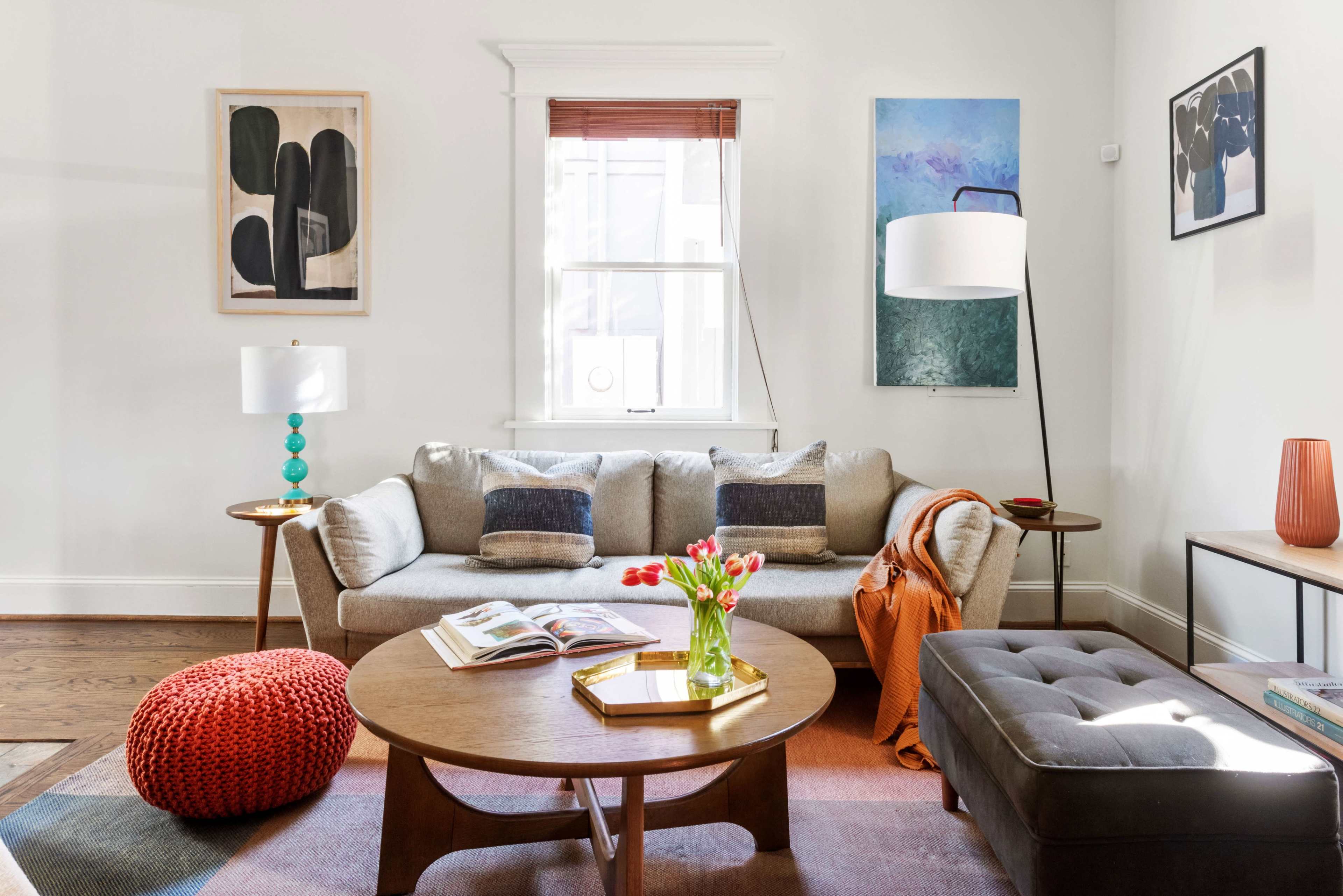 The image features a modern living room with a gray sofa, round wooden coffee table, and decorative art on the walls.