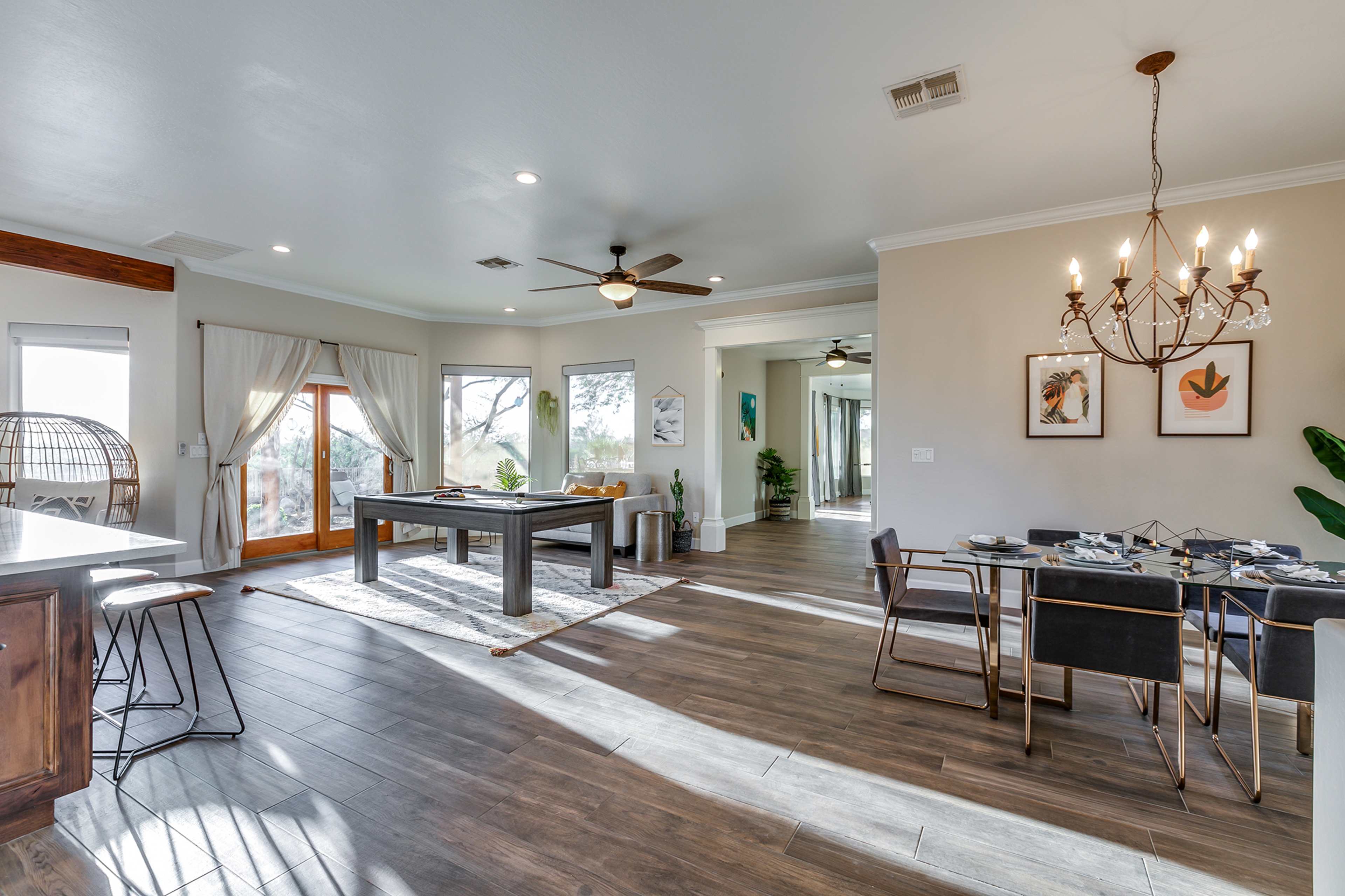 A spacious dining and living area features a pool table, dining table, and large windows with natural light.