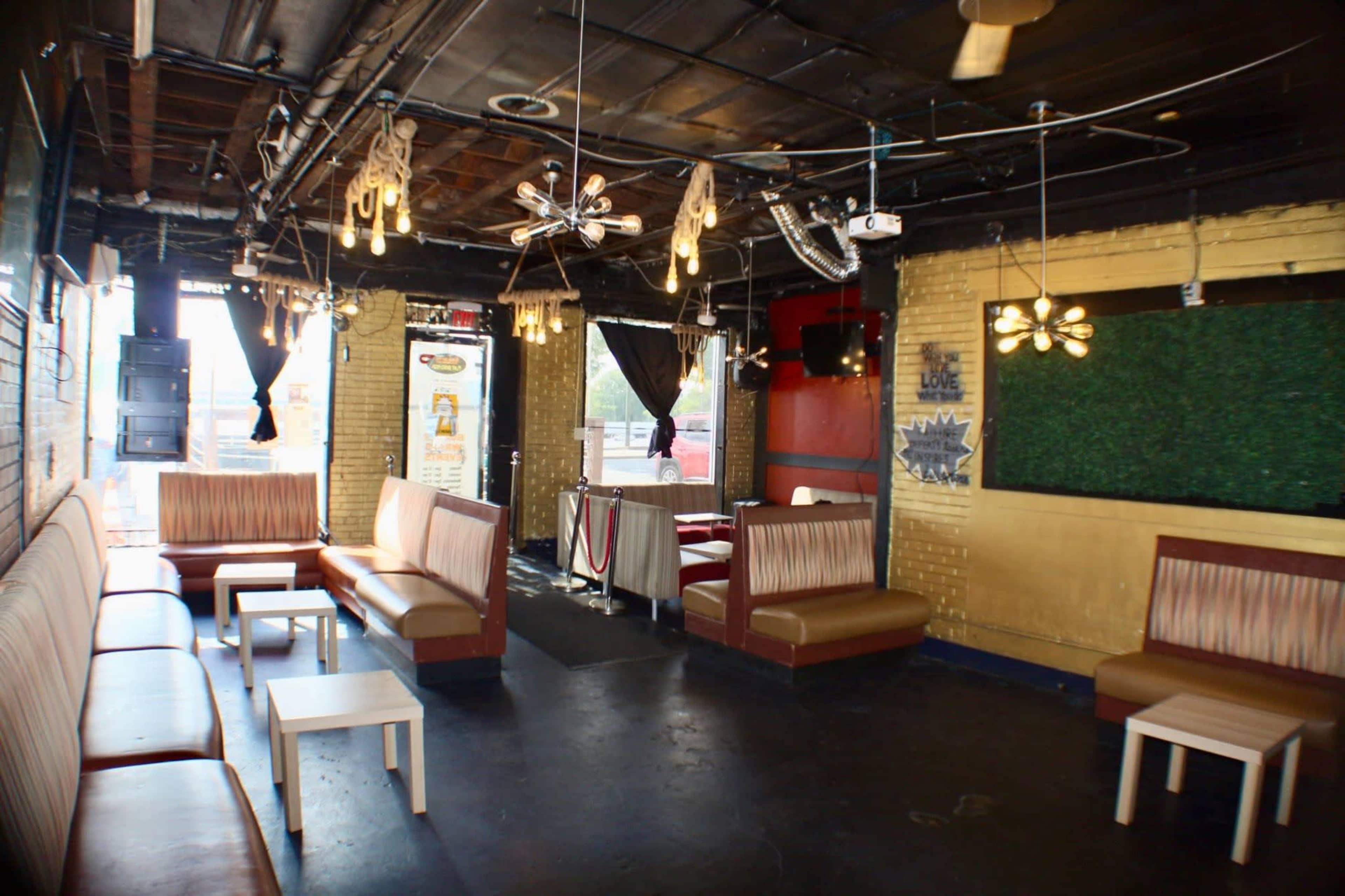 The image shows an interior of a lounge with seating areas, low lighting fixtures, and a mix of casual furniture.