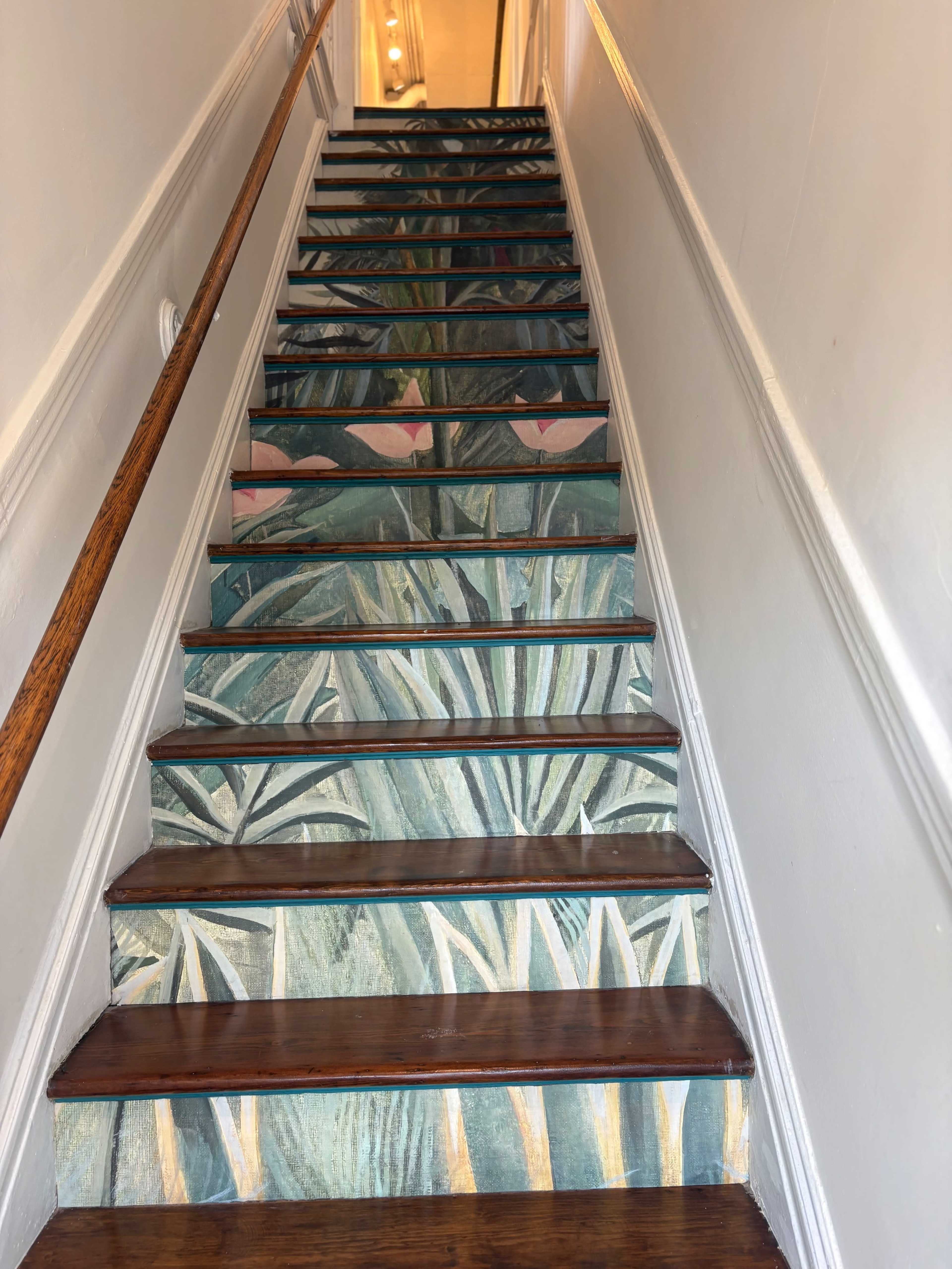 The image shows a staircase with painted foliage designs covering the steps and the wall adjacent to it.