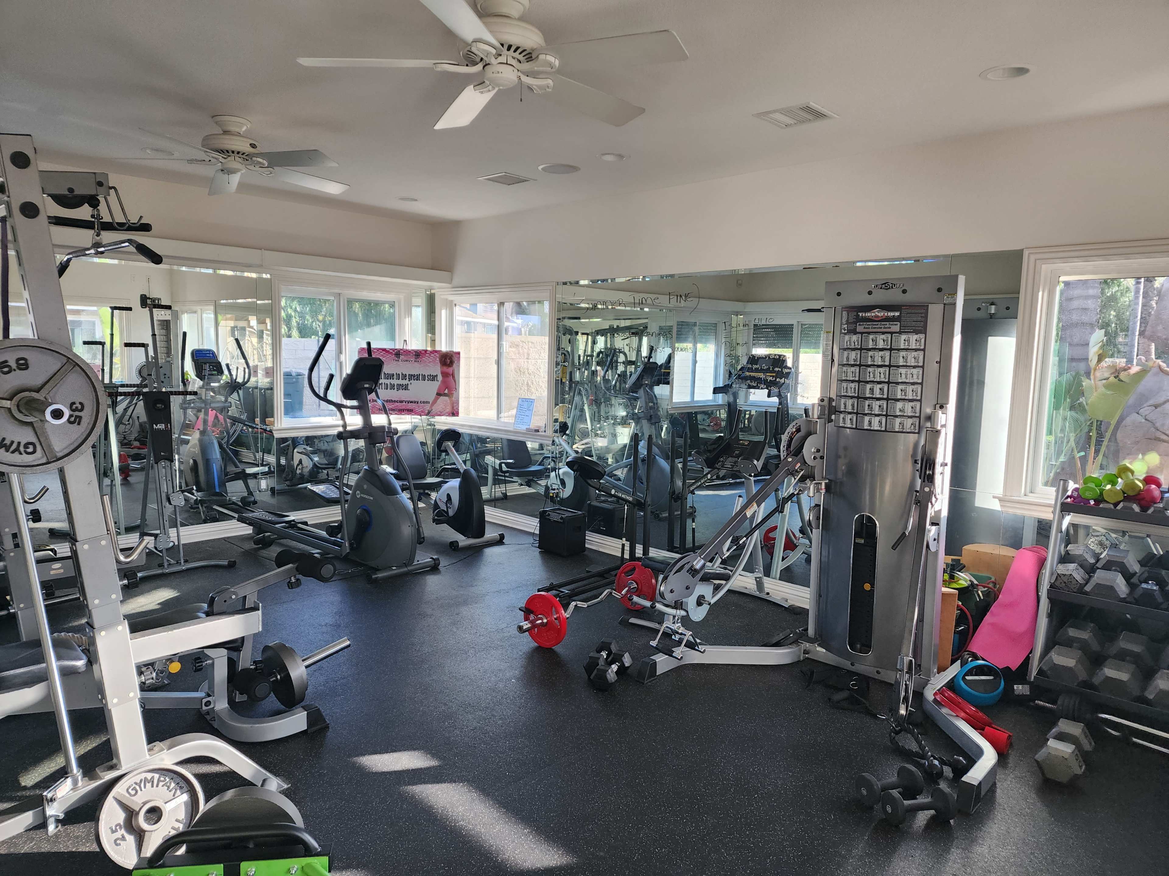 A well-equipped gym featuring various exercise machines, free weights, and mirrors along the walls.