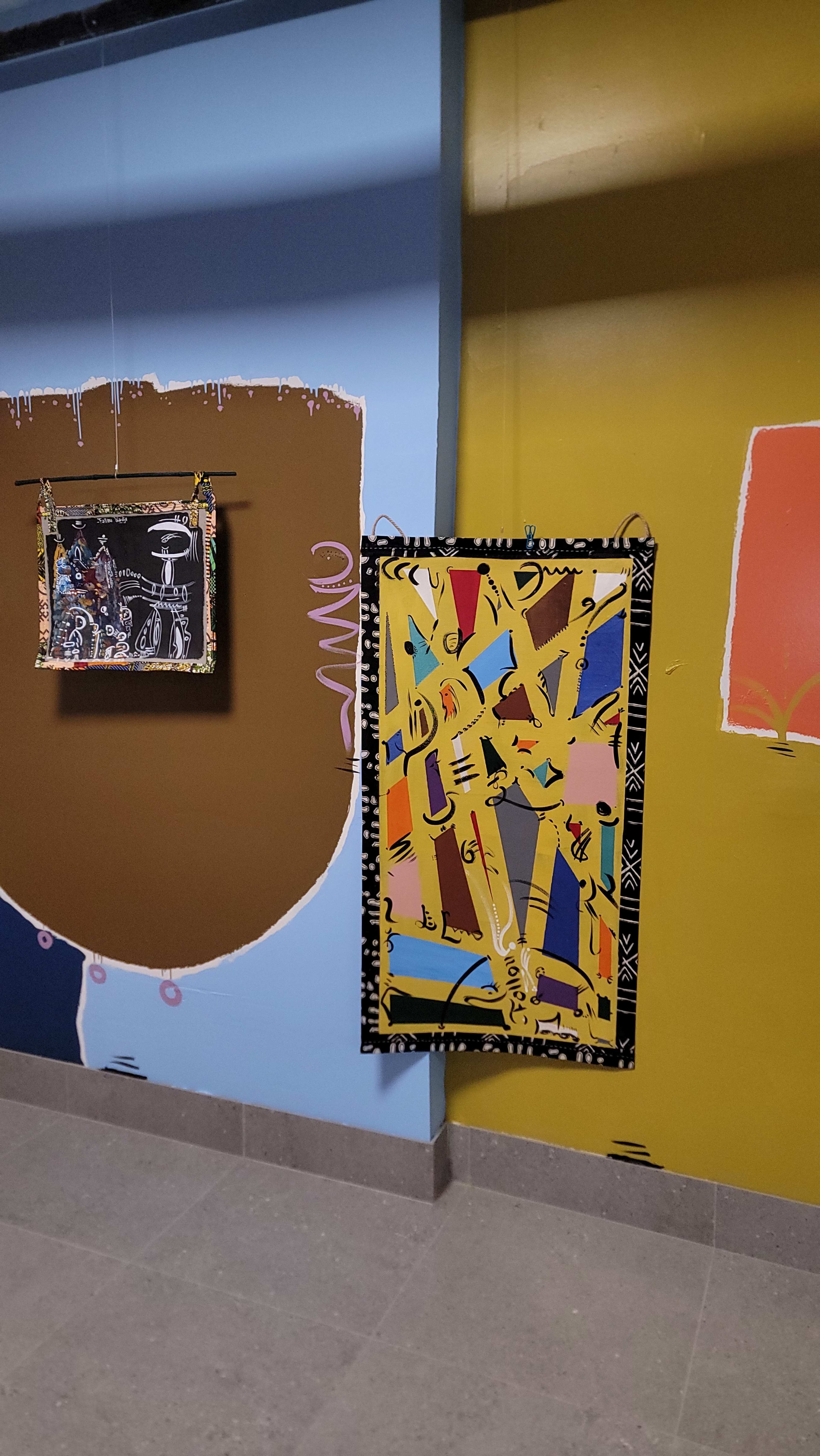 The image shows two framed artworks hanging on a wall with contrasting paint colors and patterns.