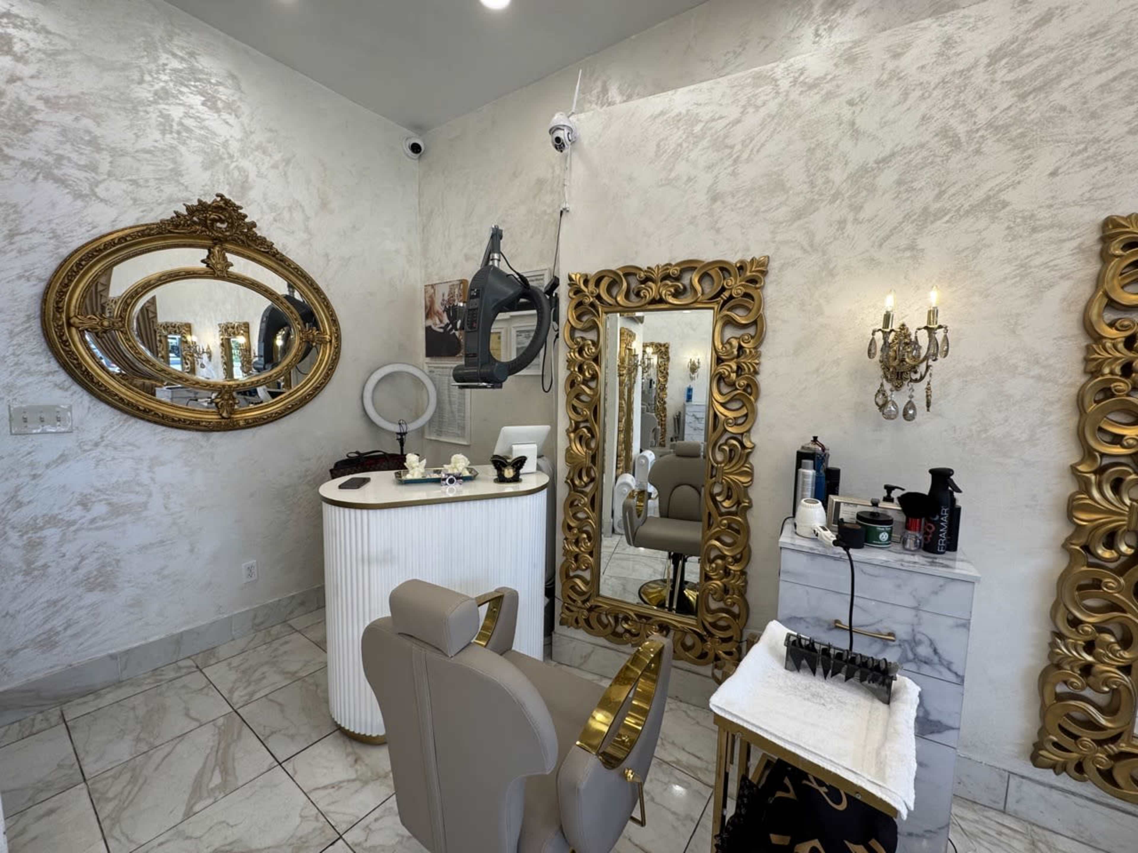 The image shows a well-decorated salon interior featuring ornate mirrors, a styling chair, and various hair care products on a counter.